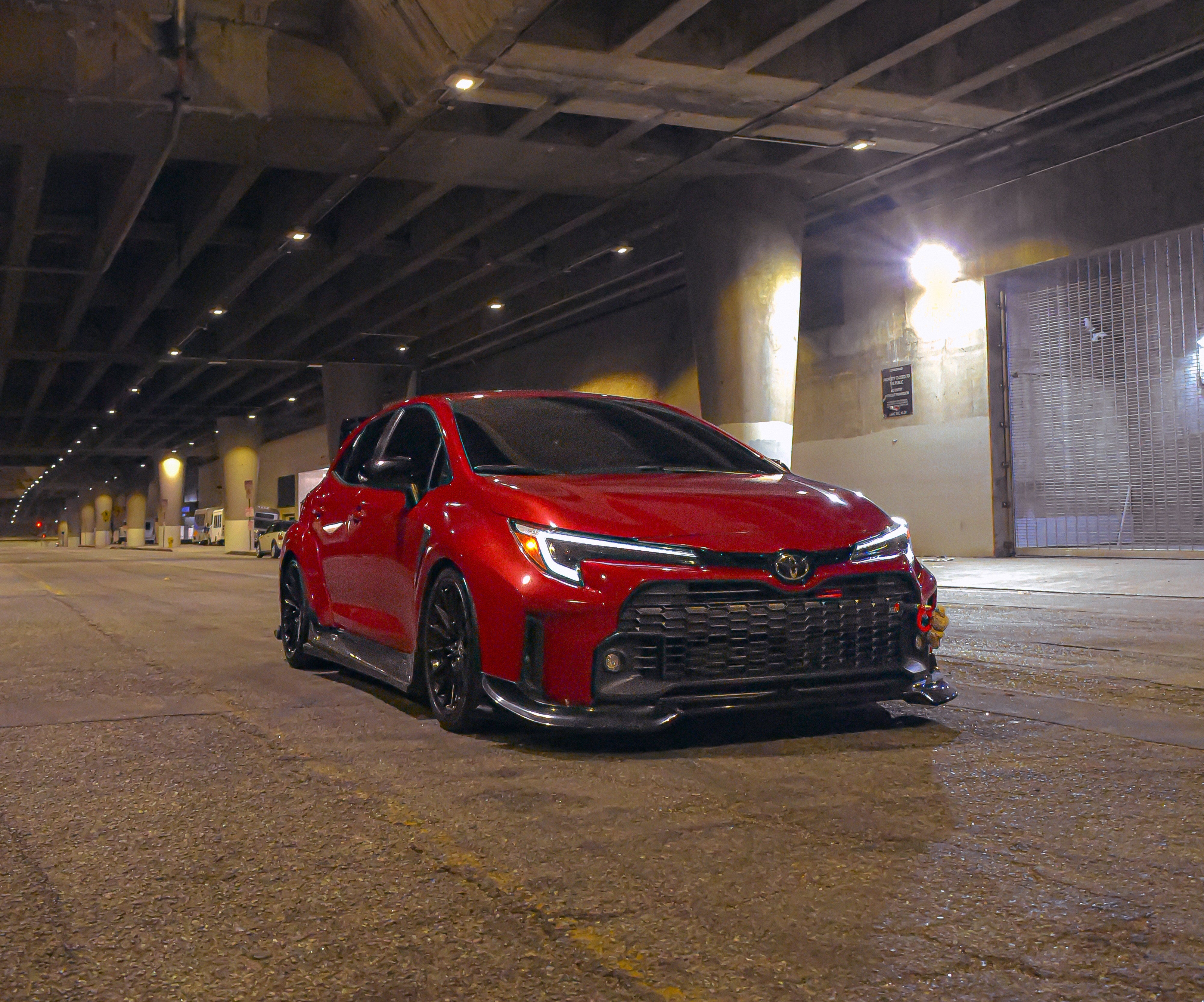 Front three-quarter view of a red GR Corolla with front lip V2 in a parking garage