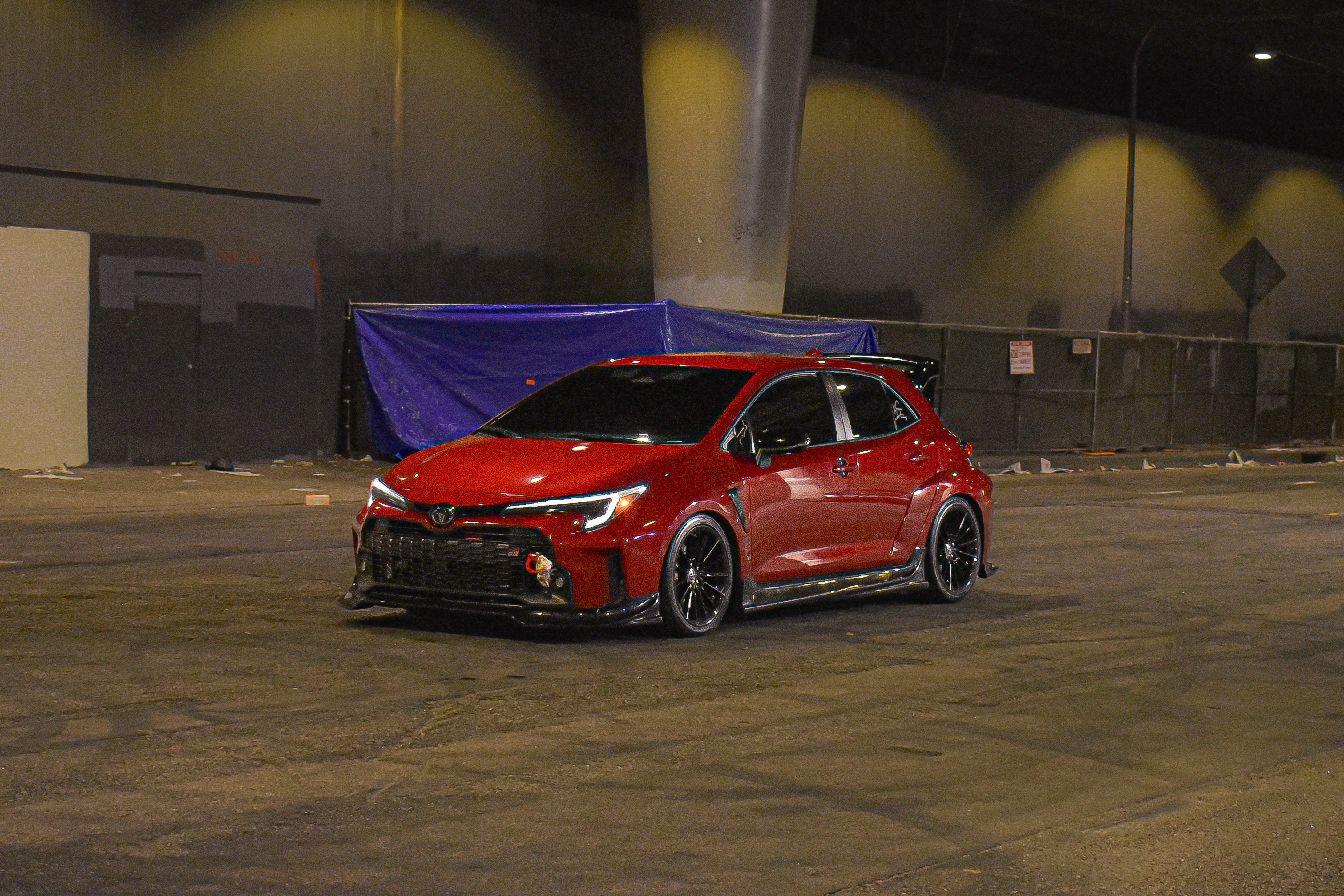 Front three-quarter view of a red GR Corolla with front lip V2 outdoors at night