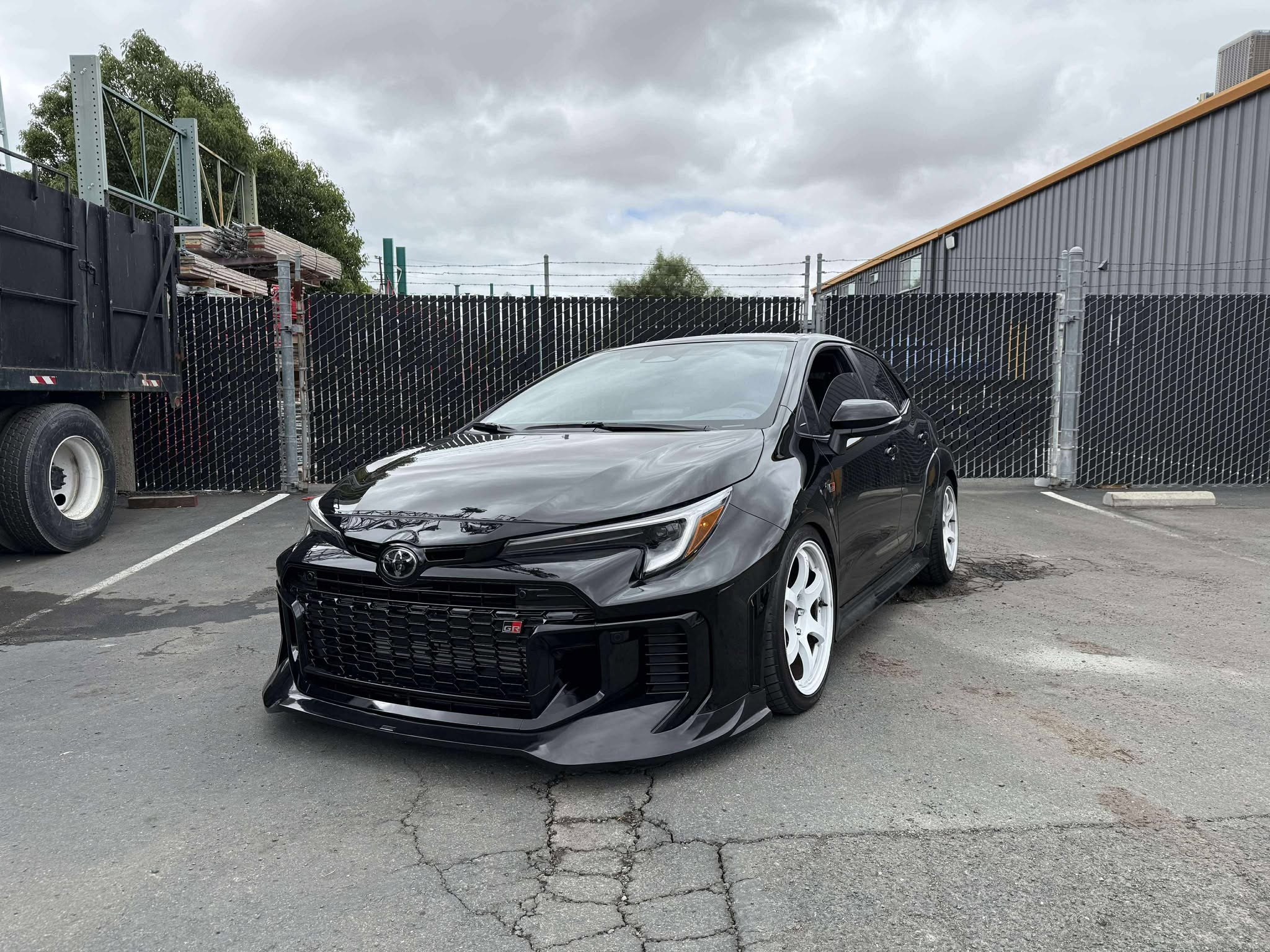 Front three-quarter view of a black GR Corolla Kouki with front lip in a parking lot