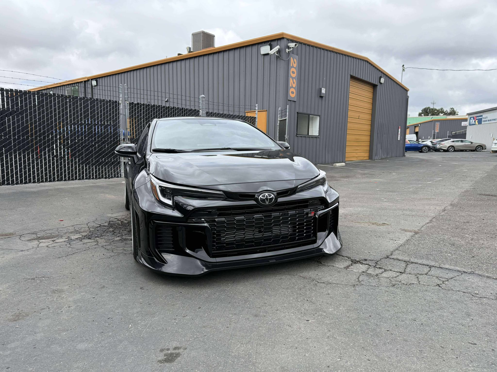 Front-on close-up of a black GR Corolla Kouki with front lip in a parking lot