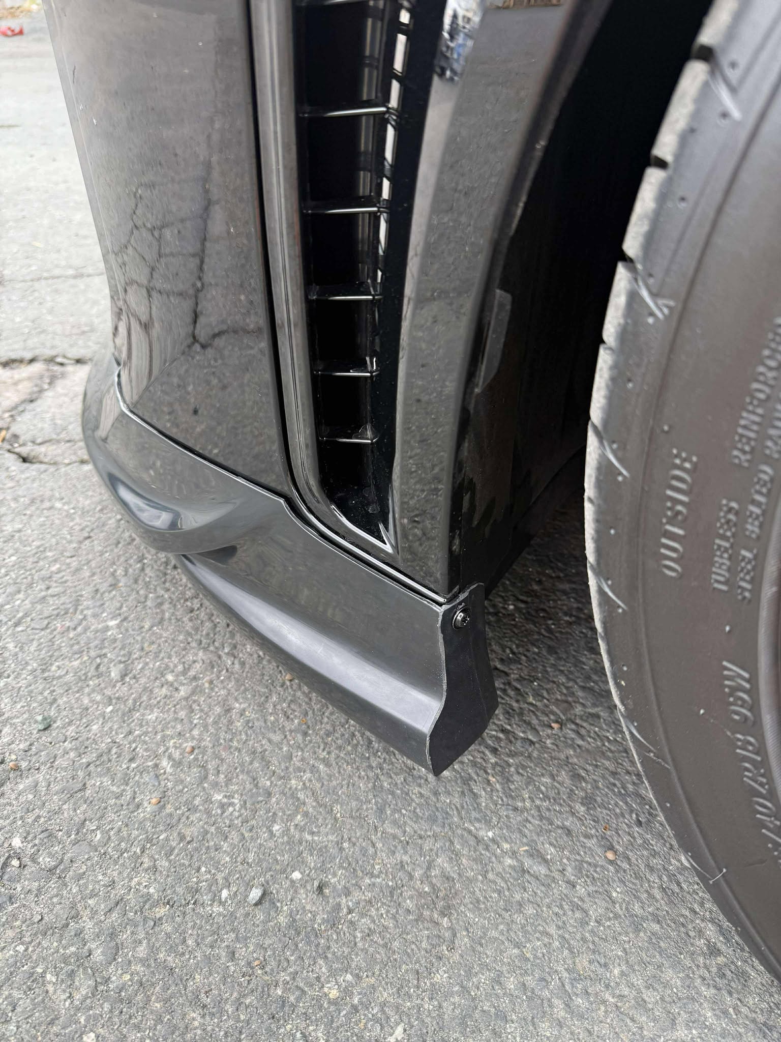 Close-up of the front lip mounting detail on a black GR Corolla Kouki bumper