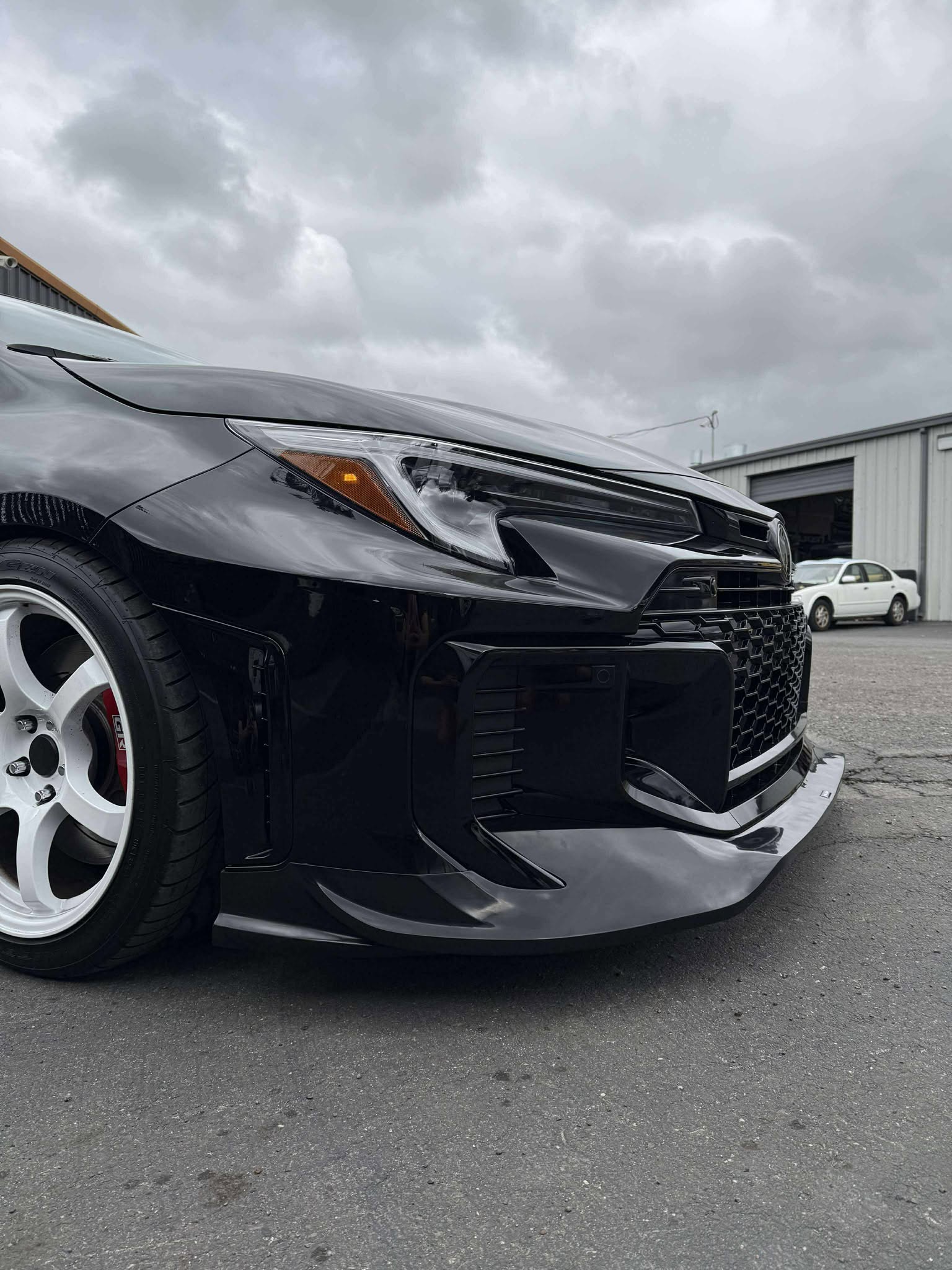 Front-on close-up of a black GR Corolla Kouki with front lip on a track