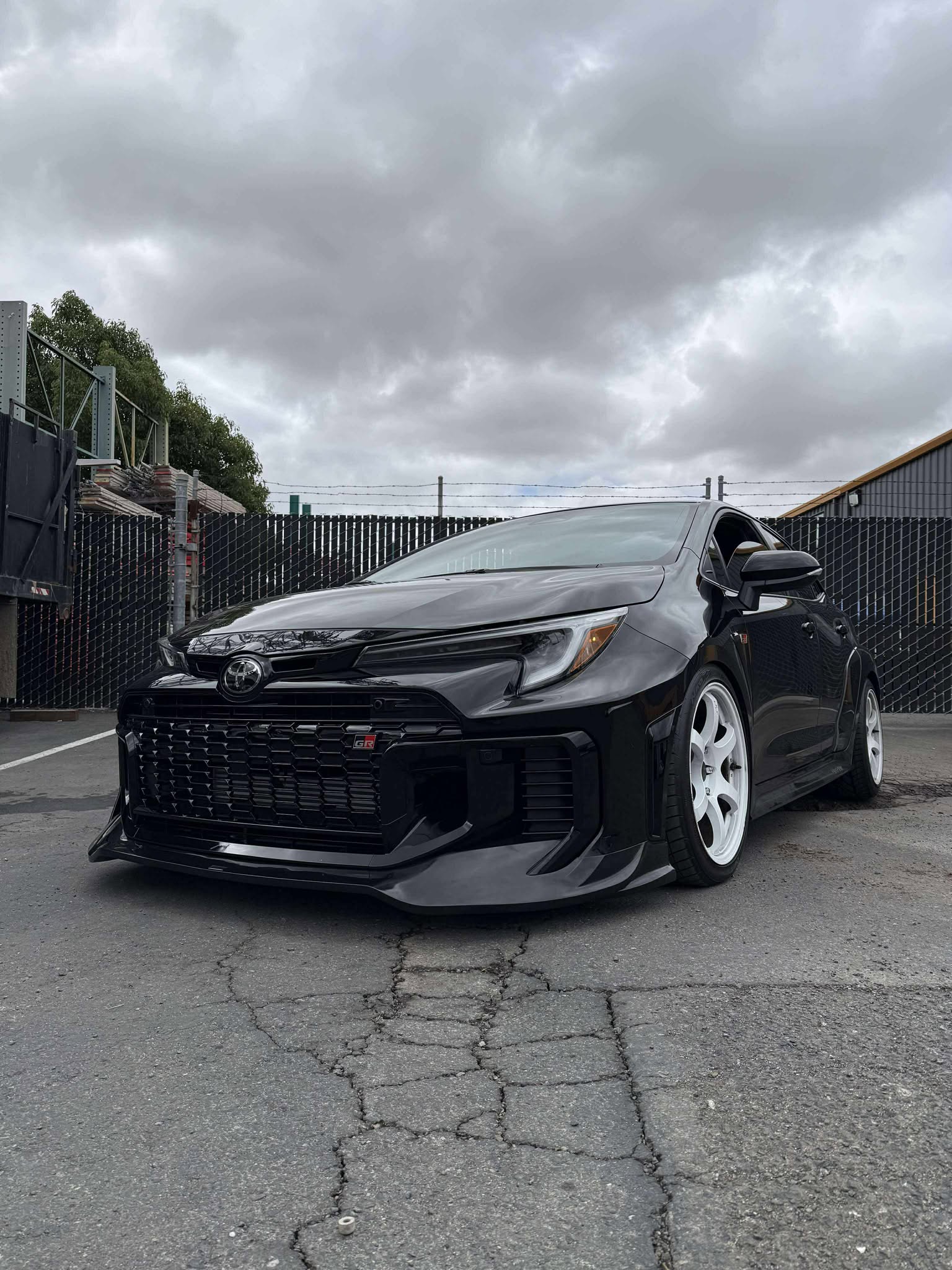 Front three-quarter close-up of a black GR Corolla Kouki with front lip and bronze wheels