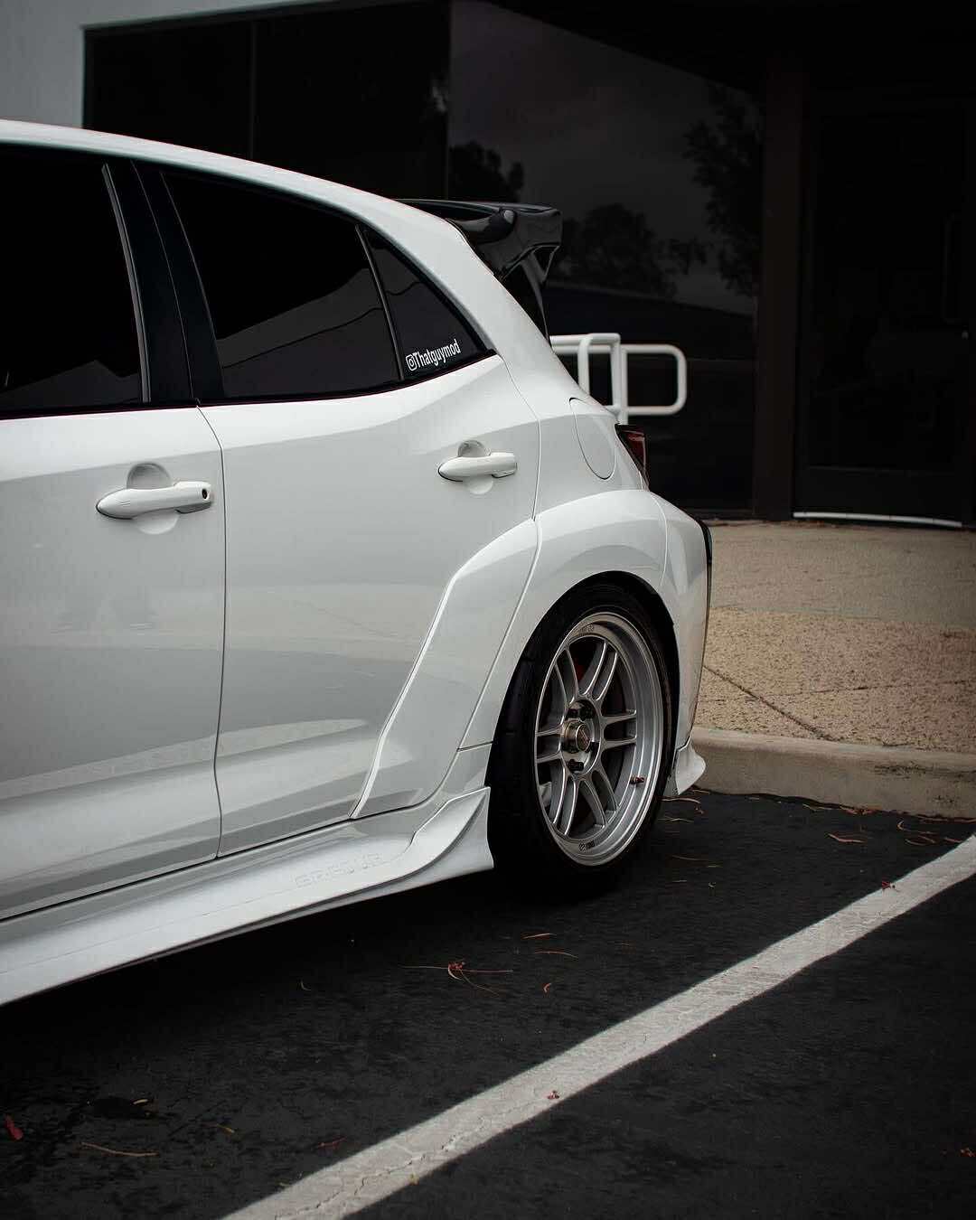 Bronze GR Corolla with side skirts parked at a billboard-lined lot