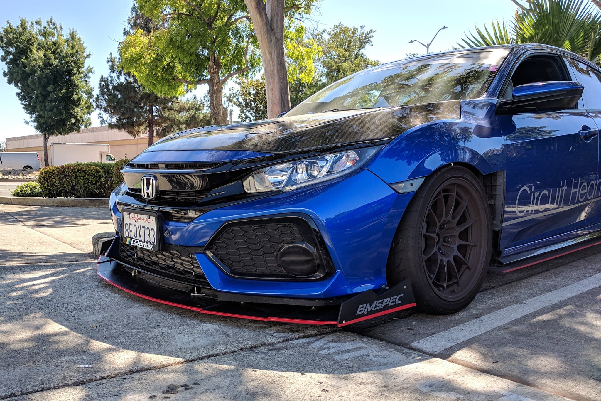 Front view of a blue Civic Hatchback Sport with front splitter and bronze wheels