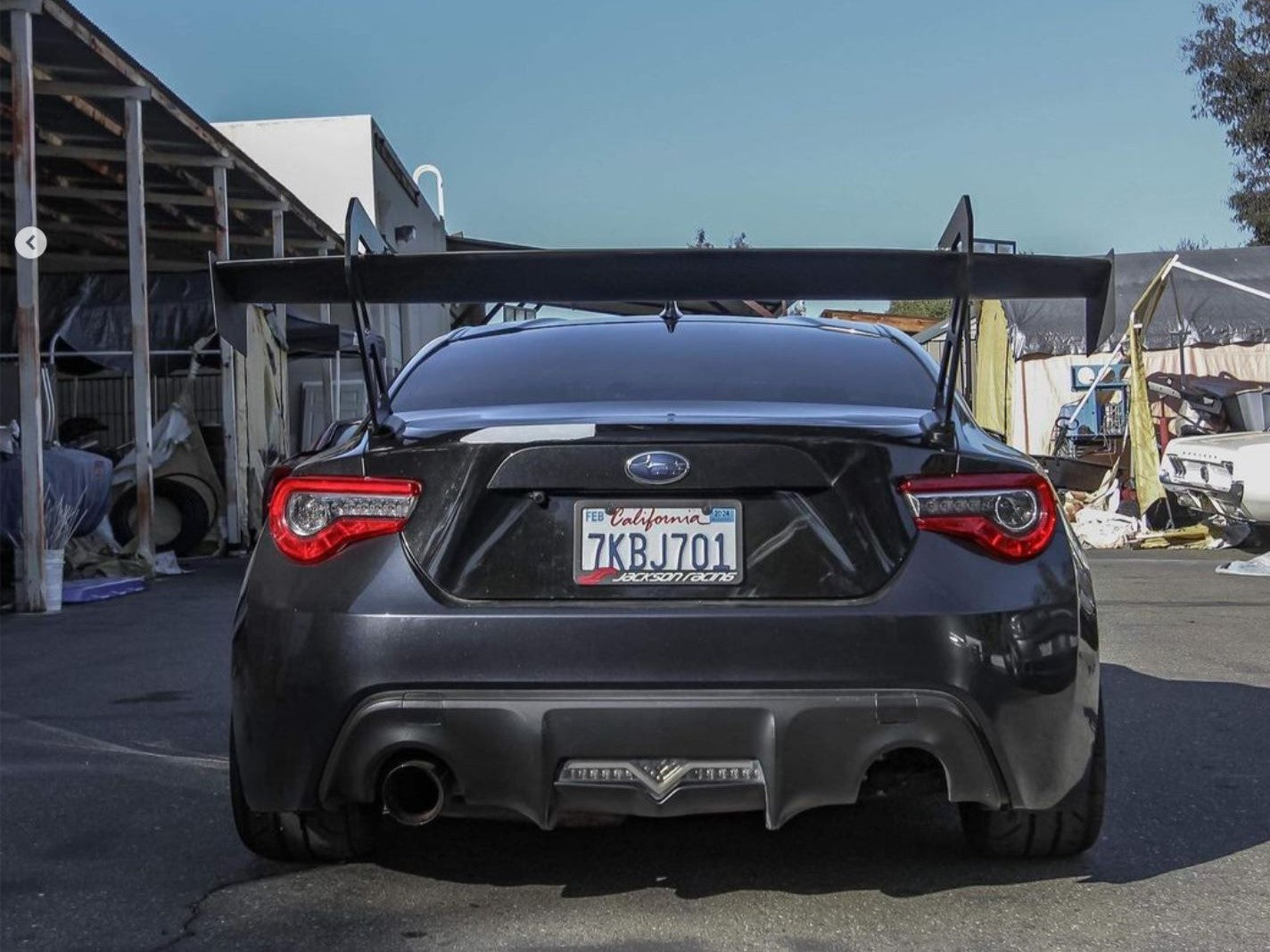 Rear straight-on view of a dark gray FRS/BRZ showing the GT wing and taillights