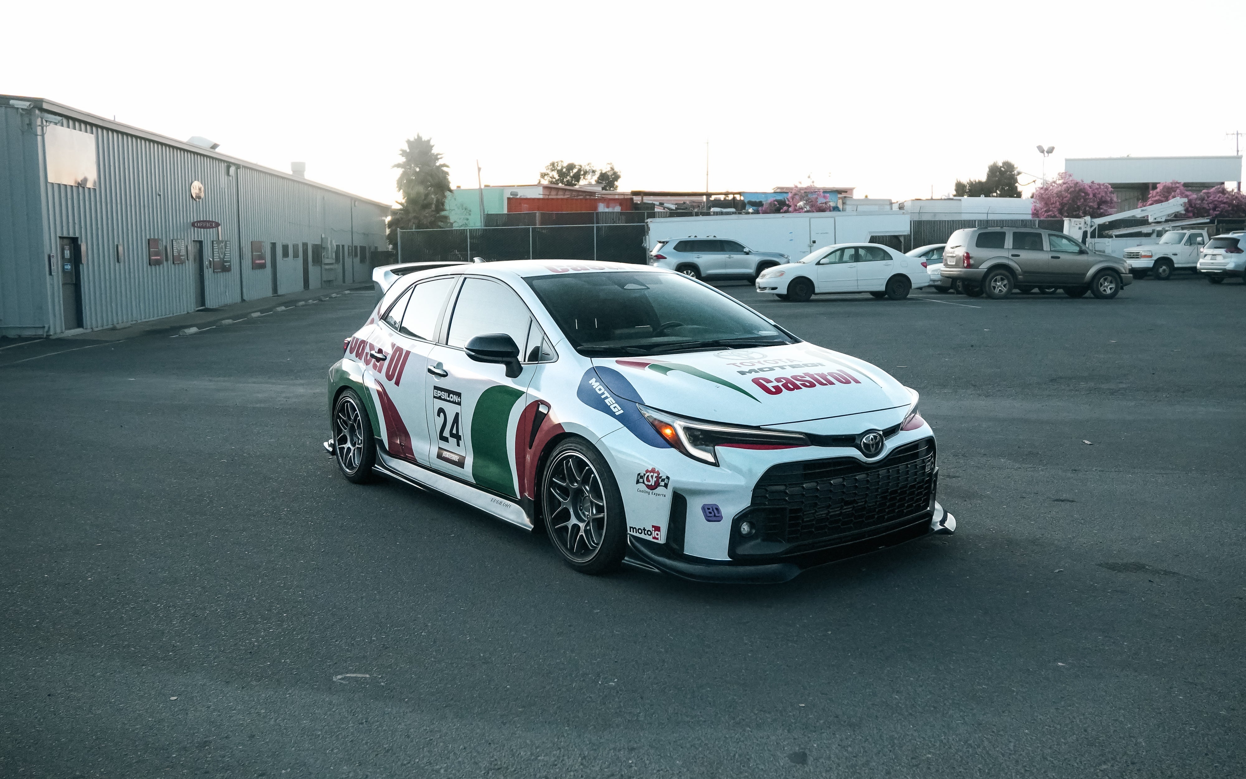 Front three-quarter view of a white and green GR Corolla rally livery car with front lip V2
