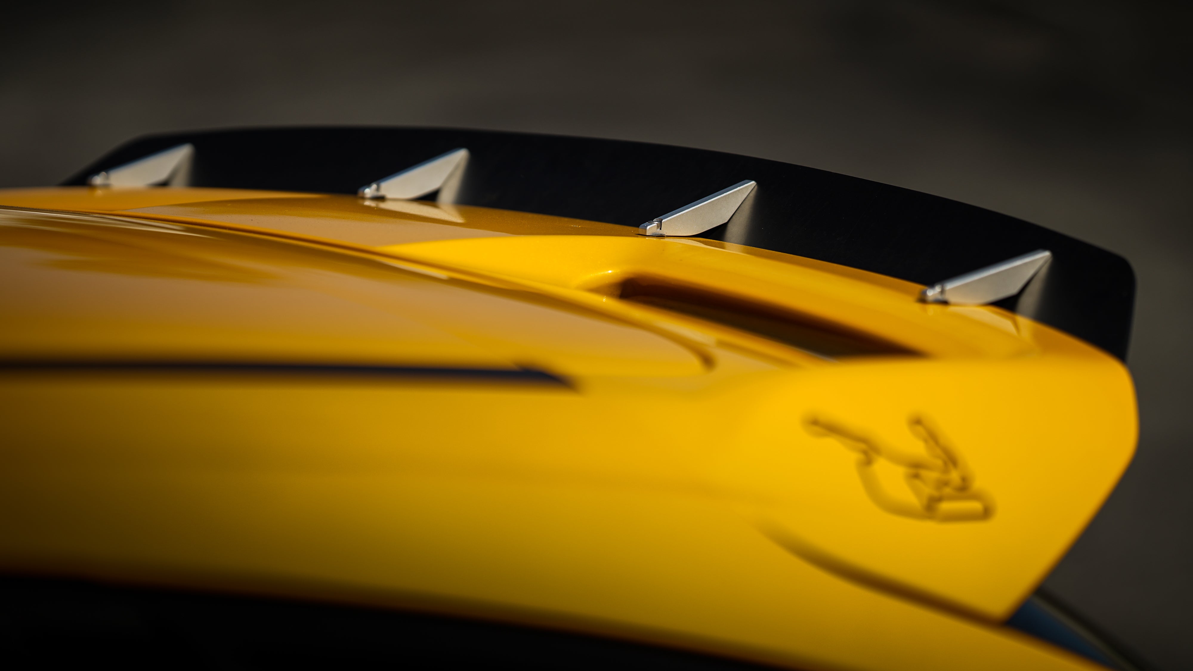 Close-up macro shot of the spoiler extension teeth on a yellow Ford Focus ST