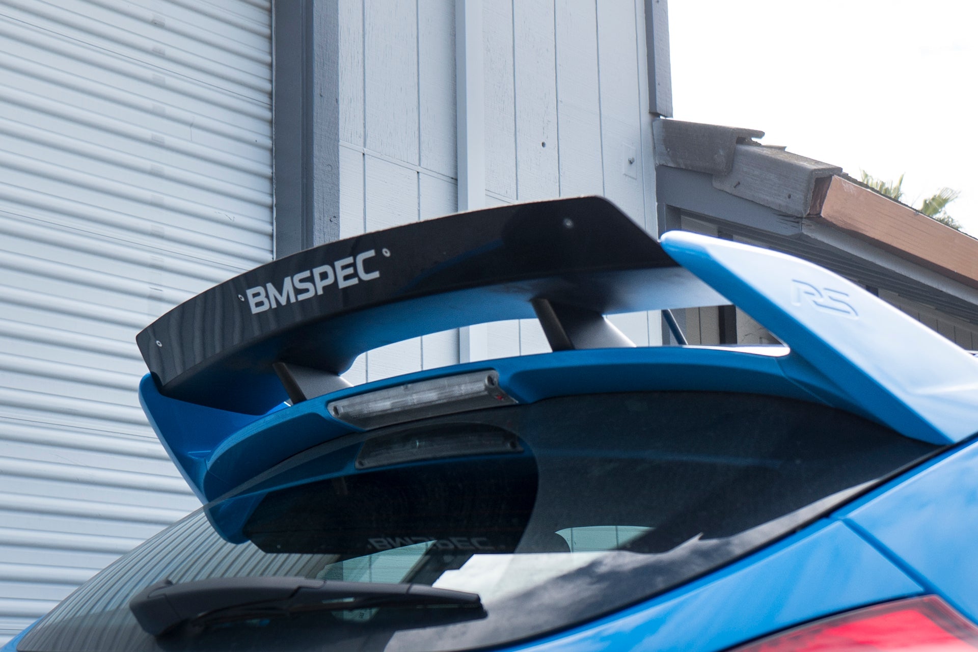Close-up of the spoiler extension mounted on a blue Focus RS OEM wing