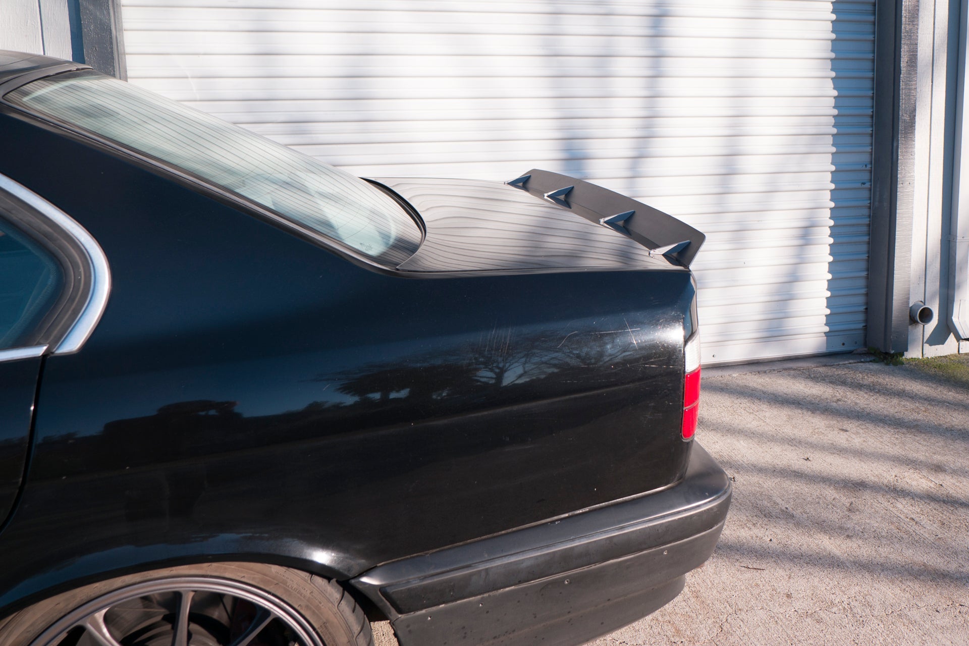 Close-up of the spoiler extension on a black BMW E34 trunk lid