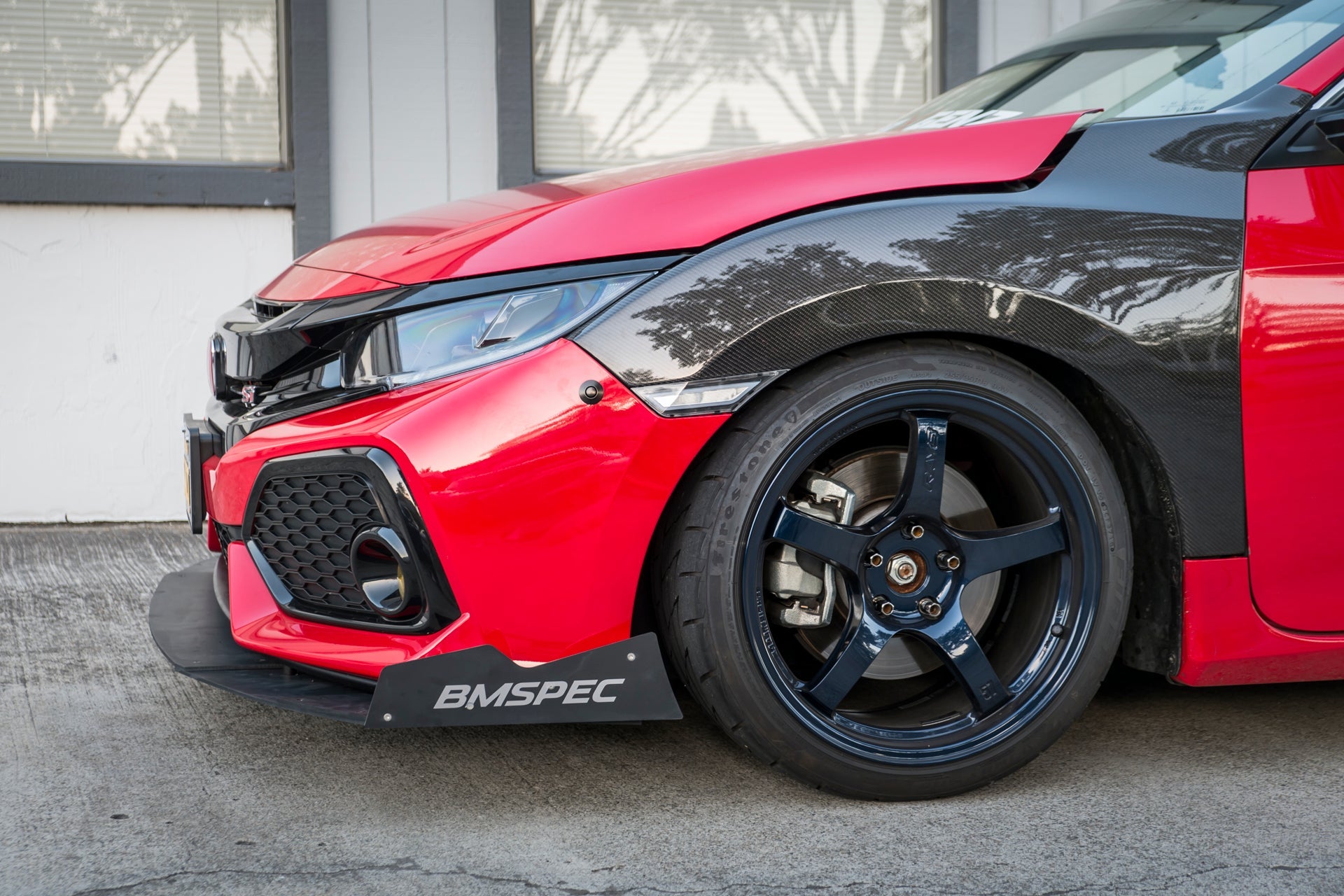 Close-up of the front splitter and fender on a red and black Civic Si Coupe