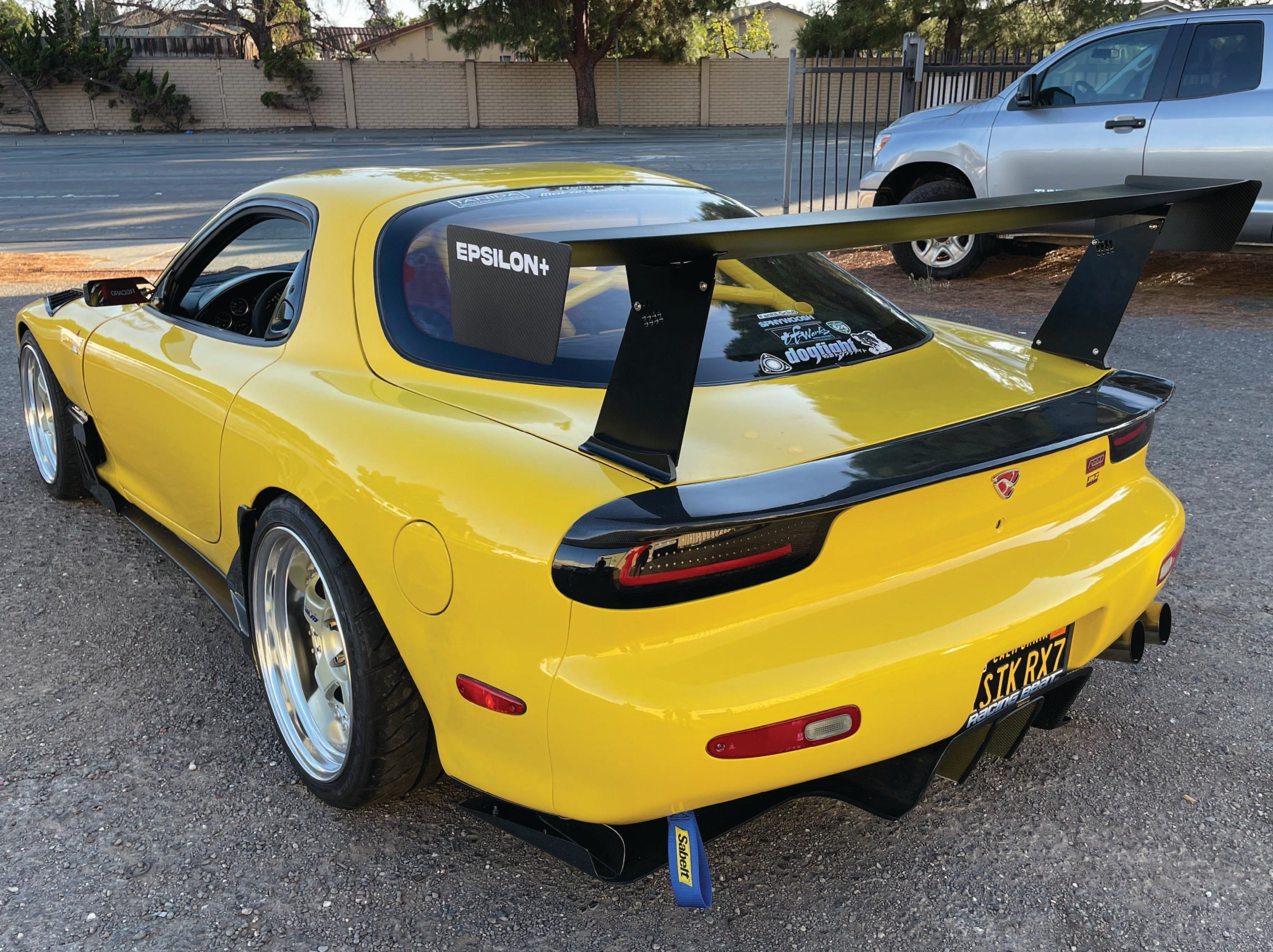 Rear view of a yellow Mazda RX-7 FD with GT wing and endplate branding