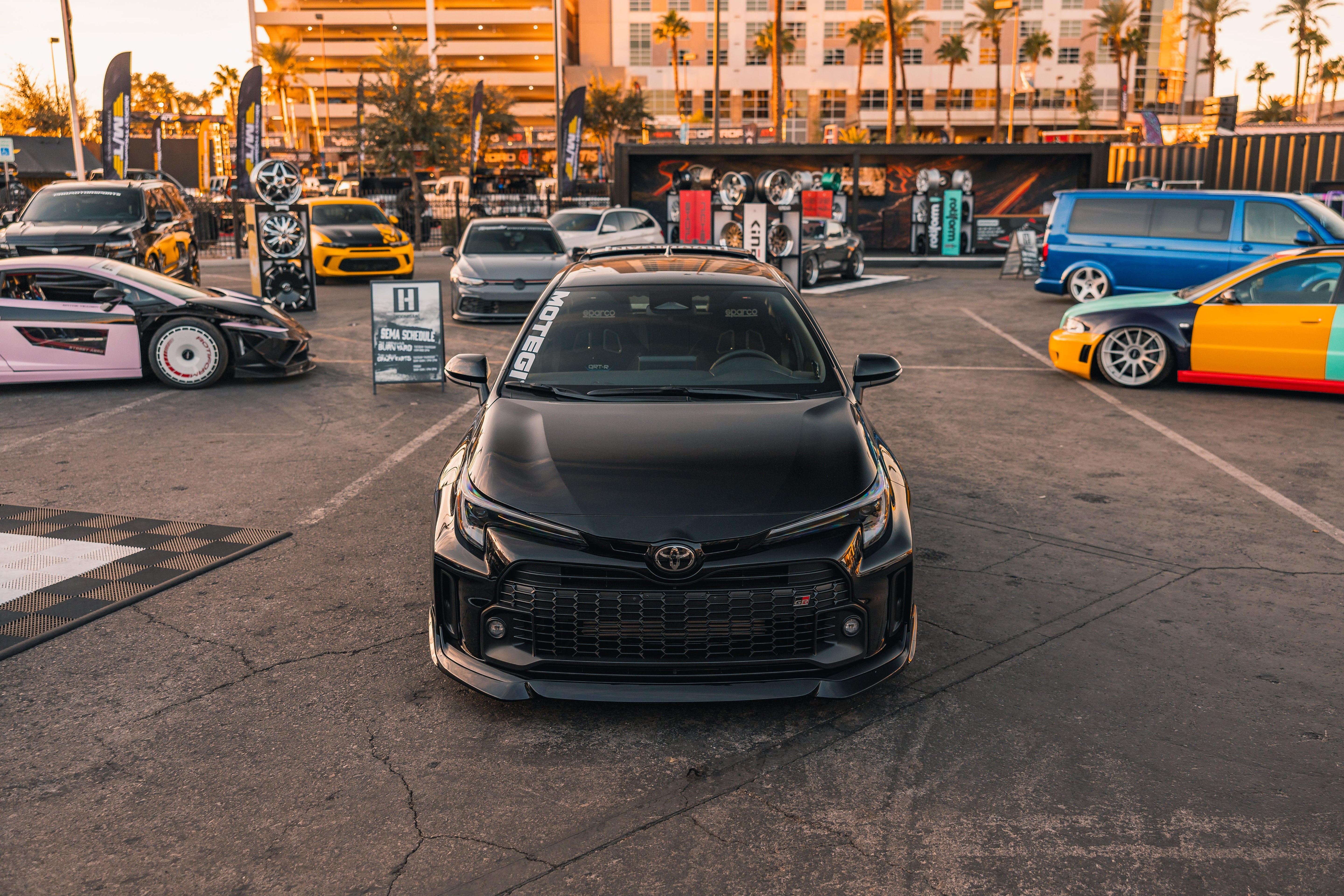 Close-up front view of a black GR Corolla with front lip at a car meet