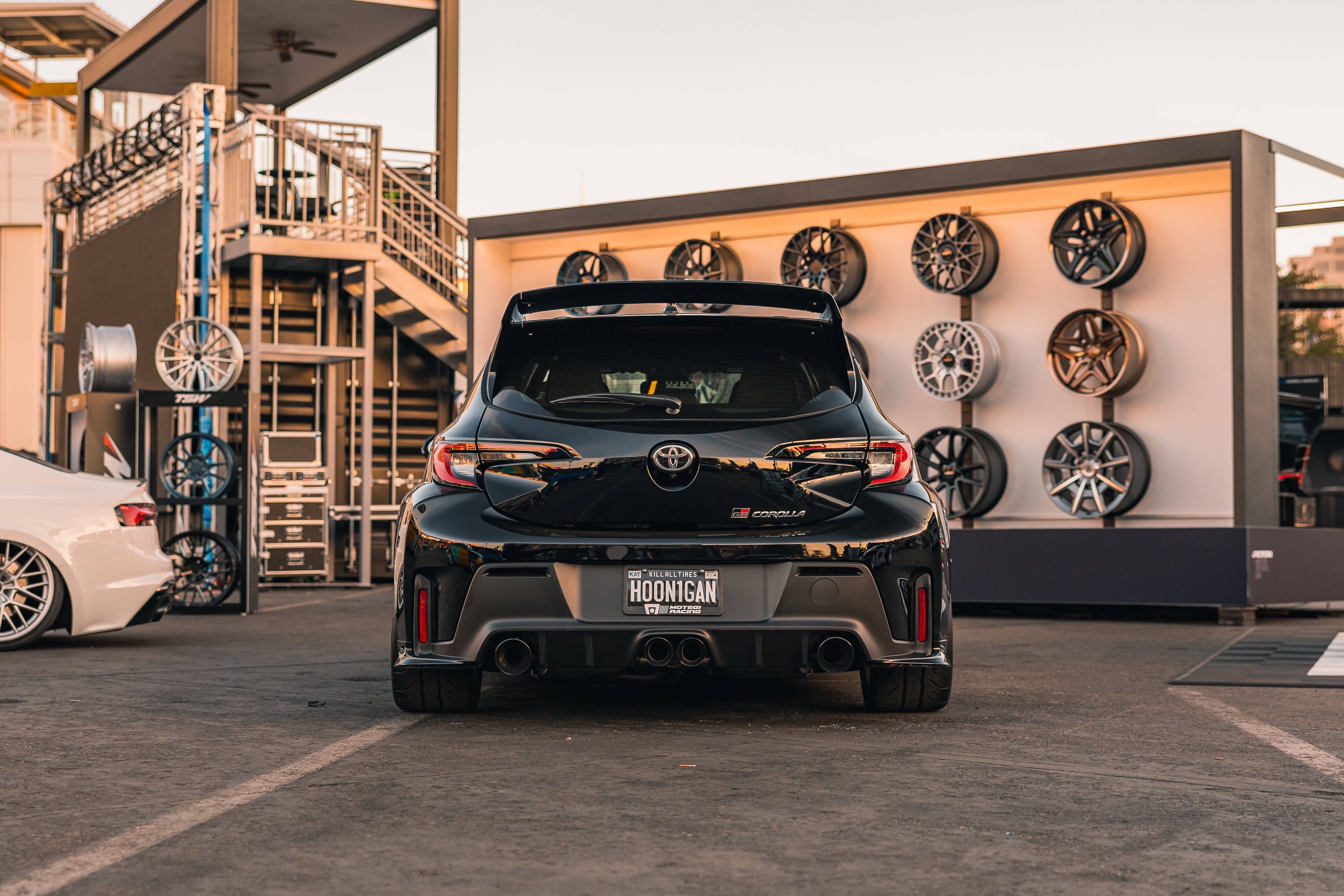 Rear view of a black GR Corolla with rear spats at a wheel display