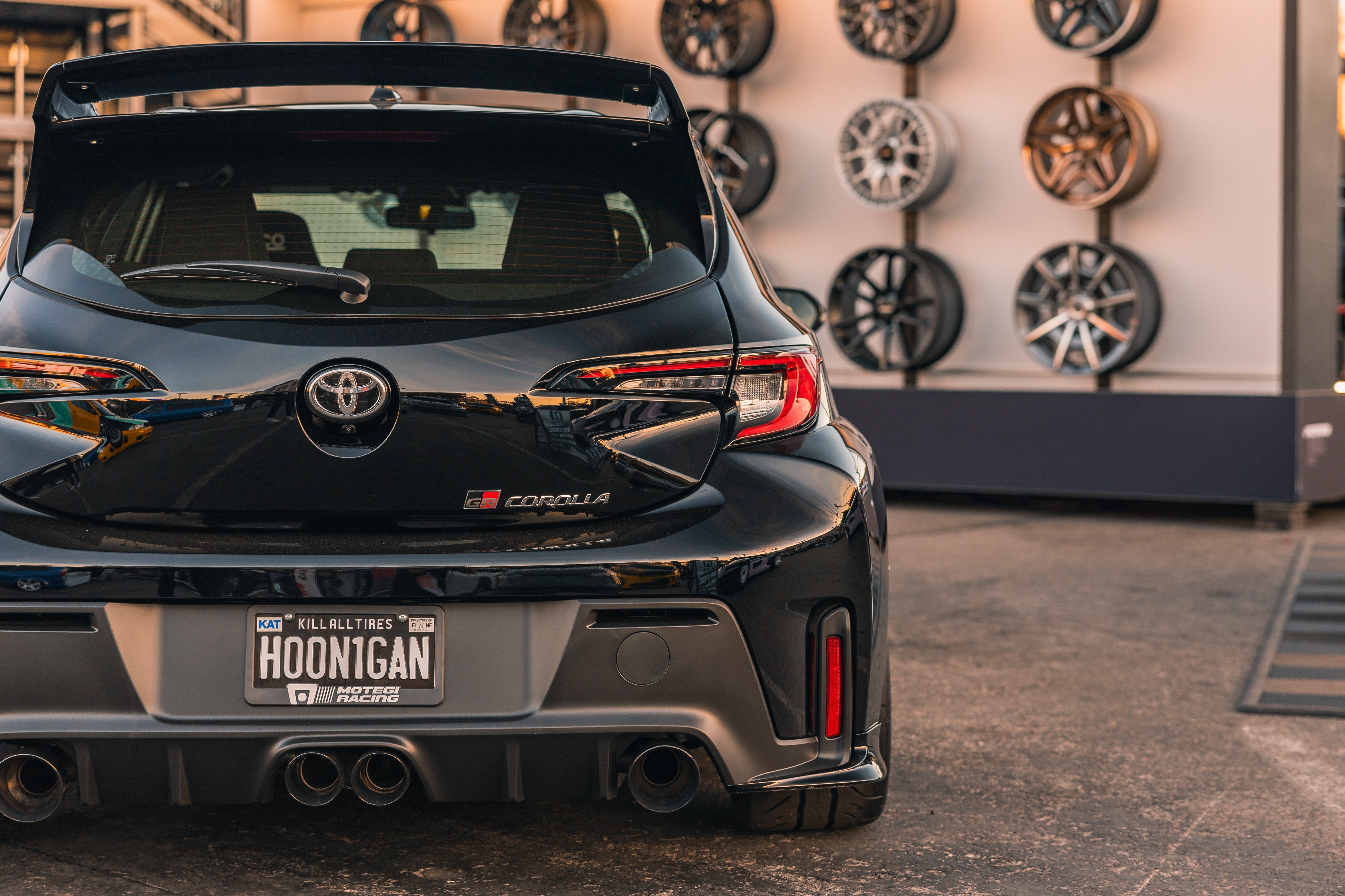 Rear three-quarter view of a black GR Corolla showing rear spats and taillights