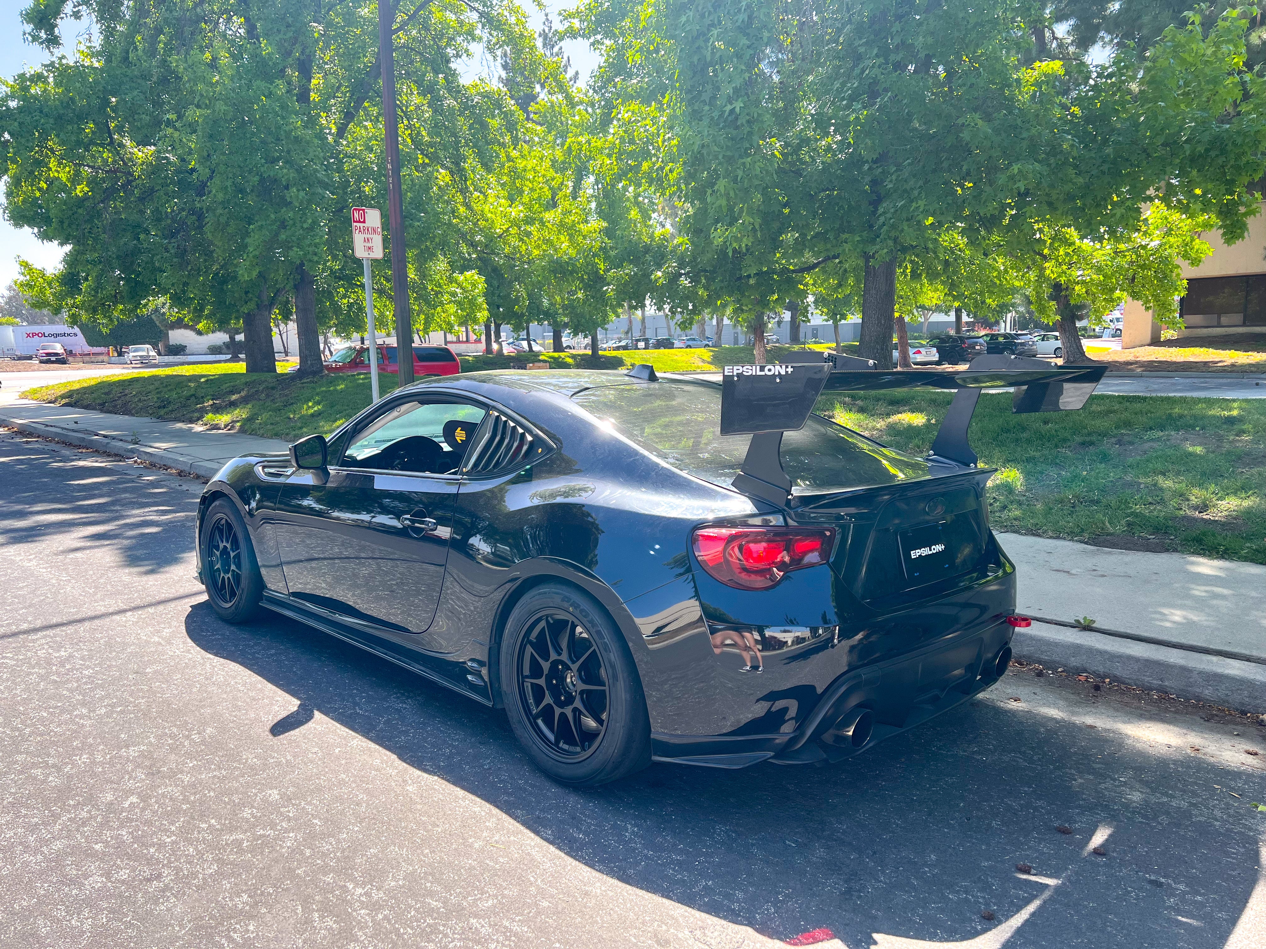 Rear three-quarter view of a dark gray FRS/BRZ with GT wing on a street