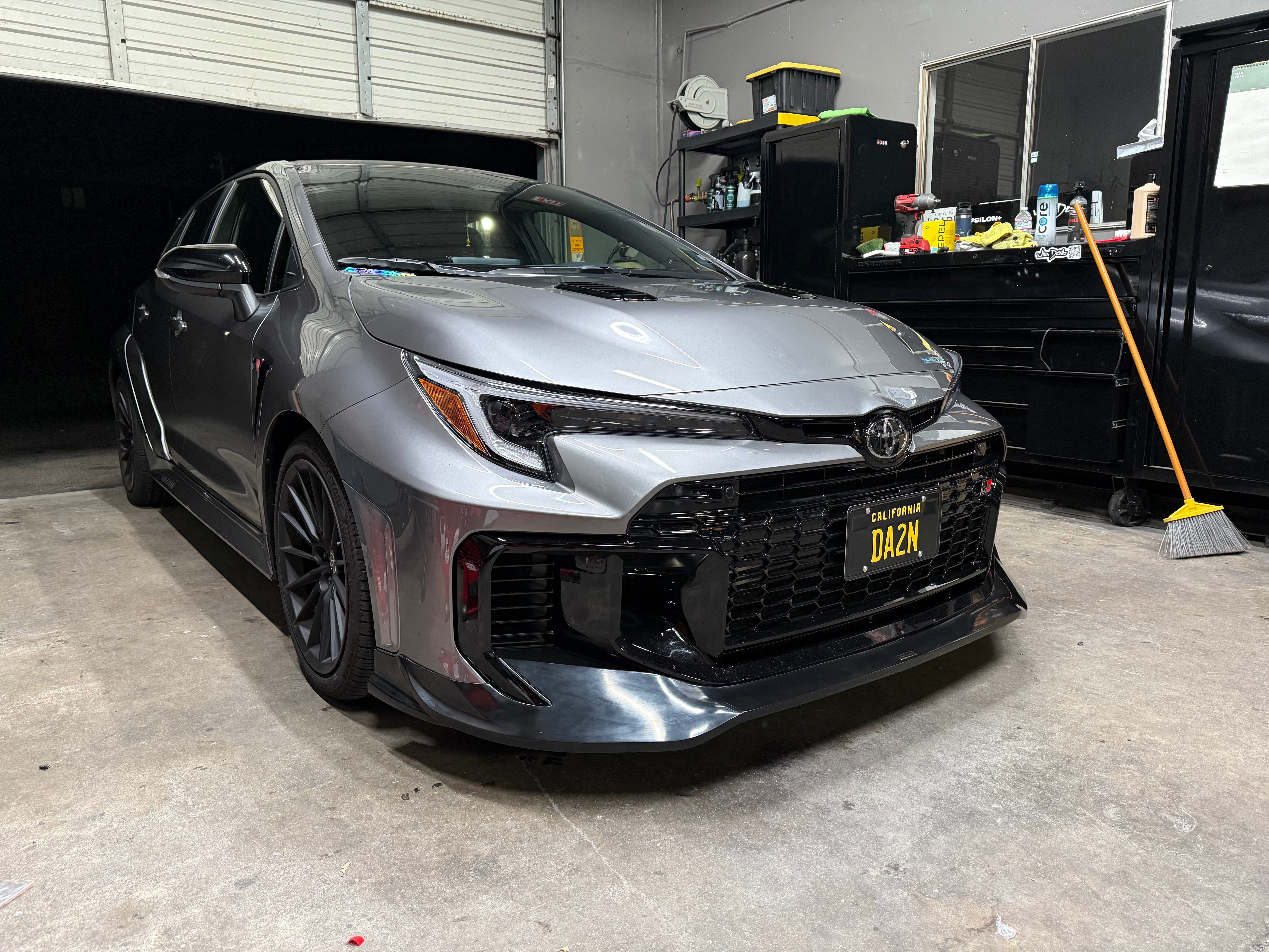 Front three-quarter view of a gray GR Corolla Kouki with front lip in a garage