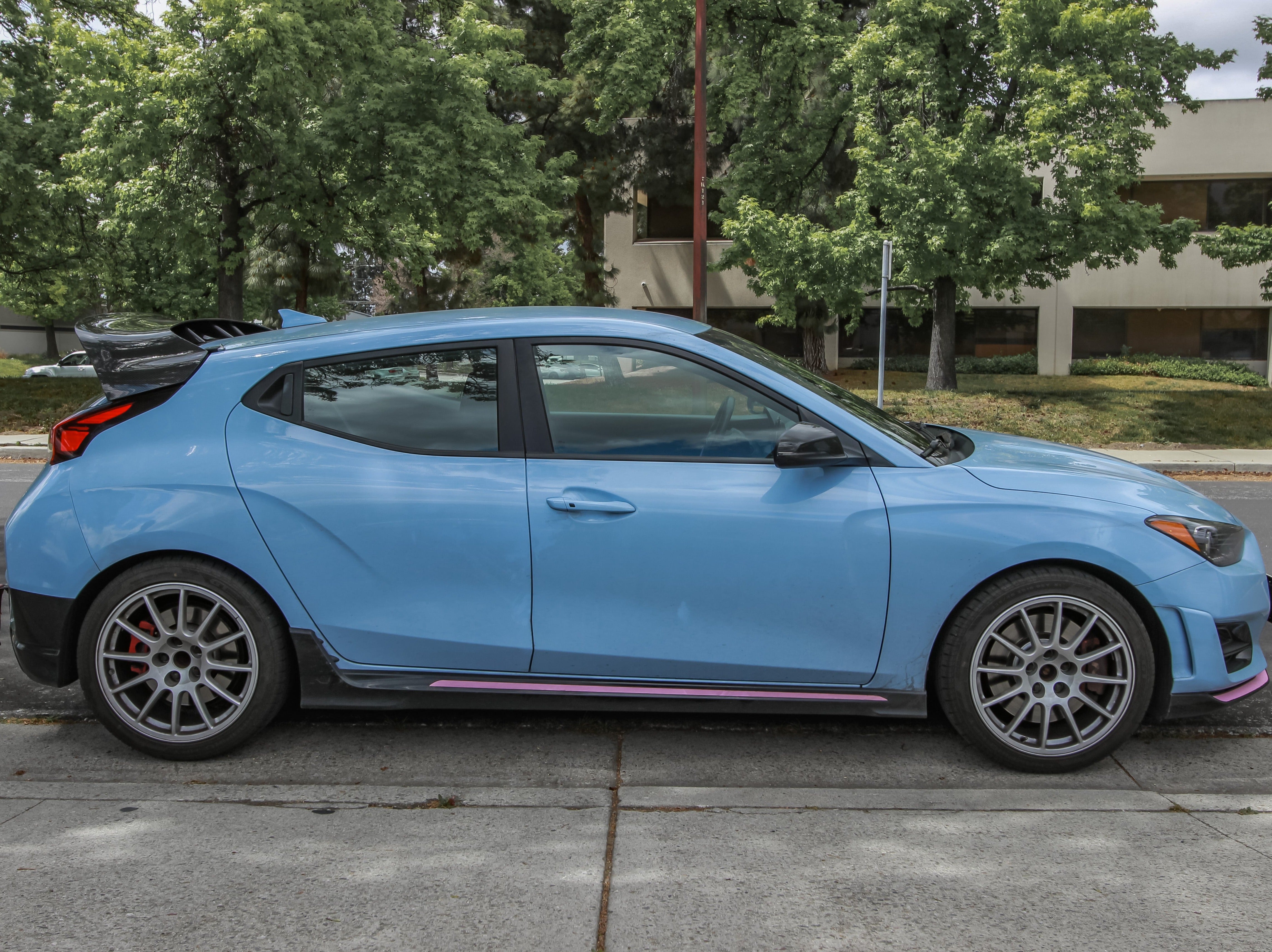 Close-up of the carbon fiber WRC Wing V2 mounted on a blue Veloster N roofline