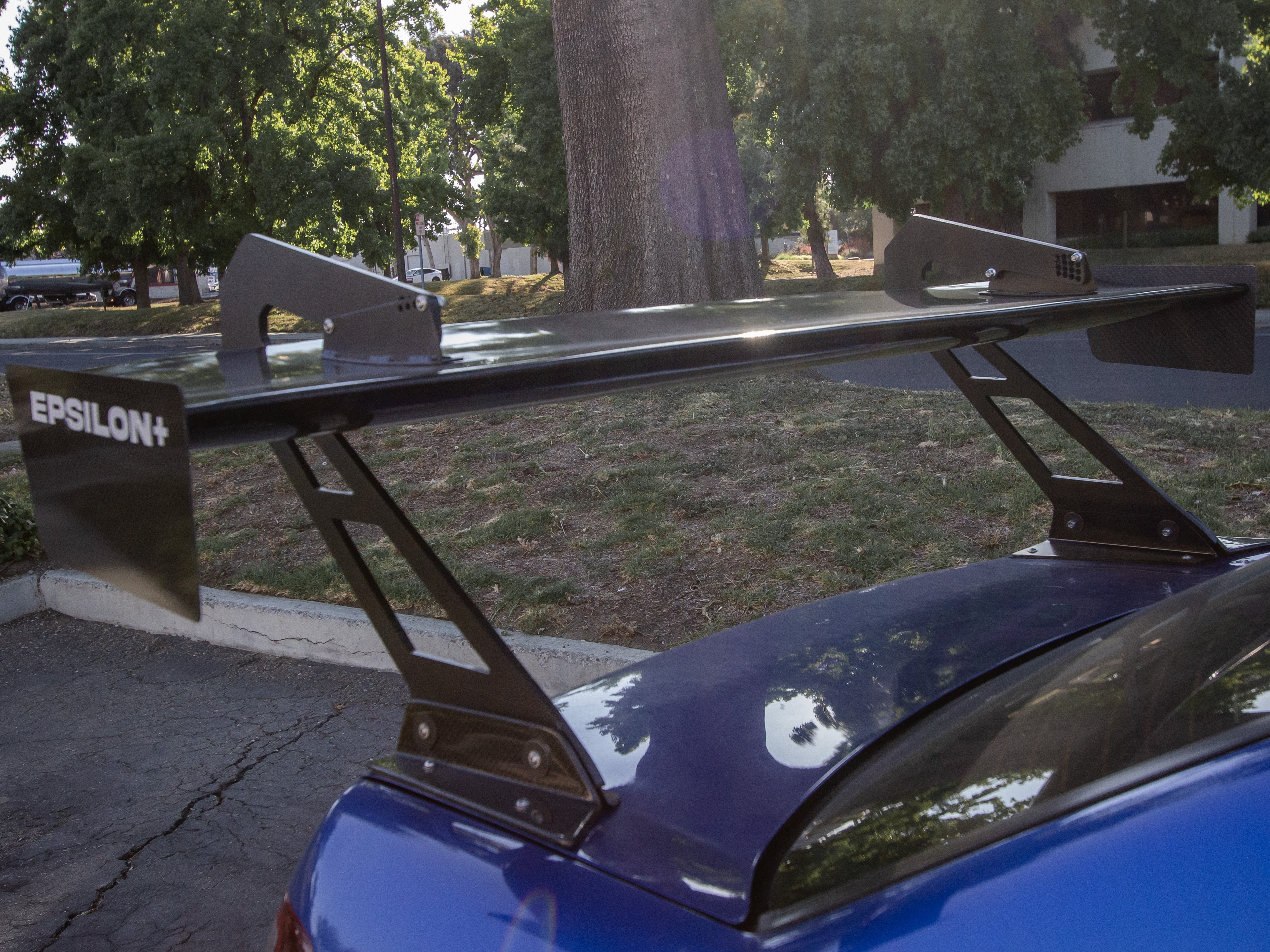 Close-up of the Epsilon+ GT wing riser and endplate on a blue Impreza GD