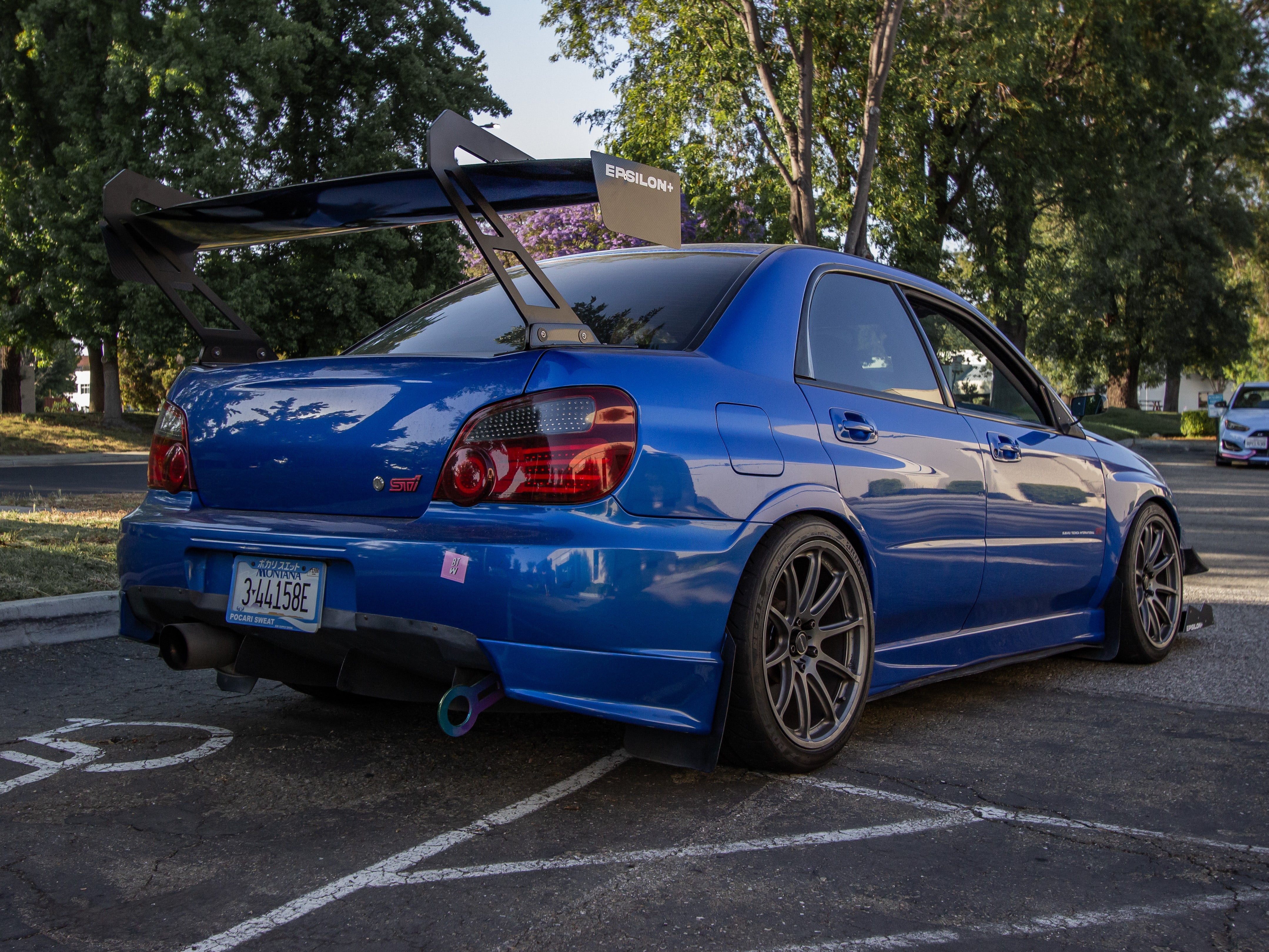 Rear three-quarter view of a blue Subaru Impreza GD with GT wing in a parking lot
