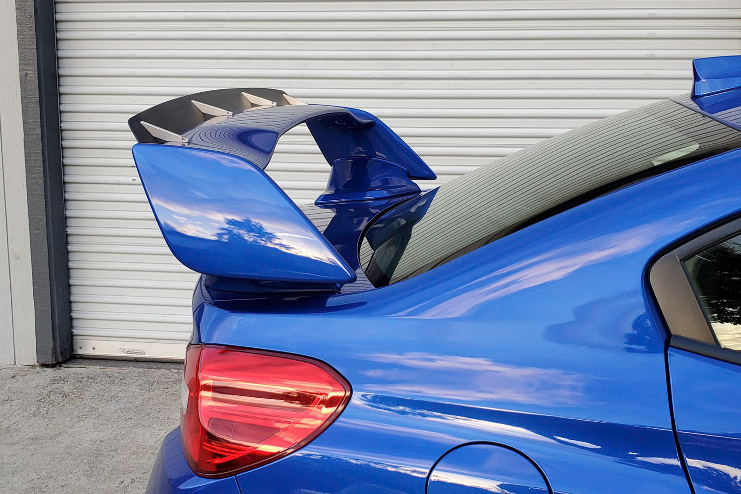 Close-up of the carbon fiber spoiler extension mounted on a blue STI VA wing