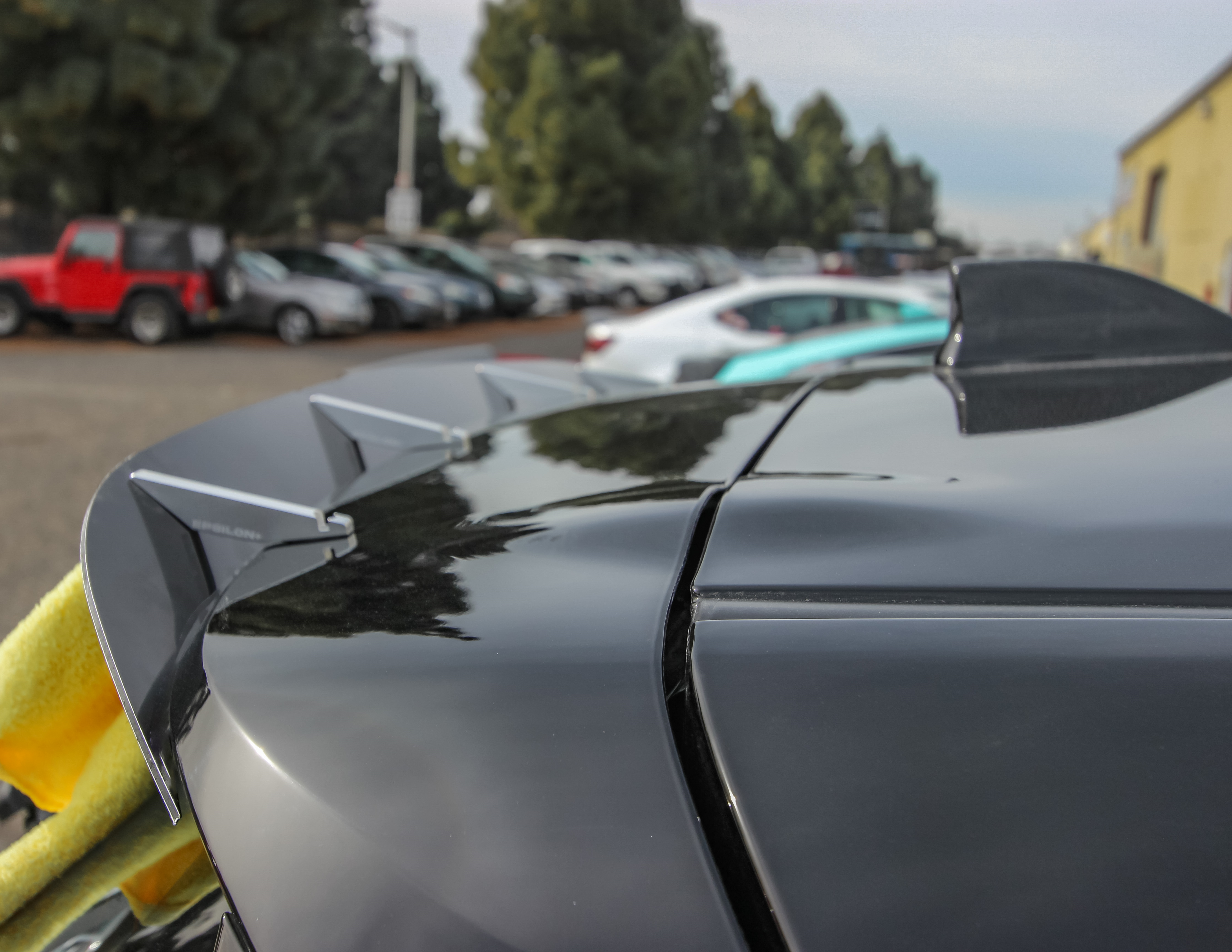 Close-up of the spoiler extension mounted on a black GR Corolla wing outdoors