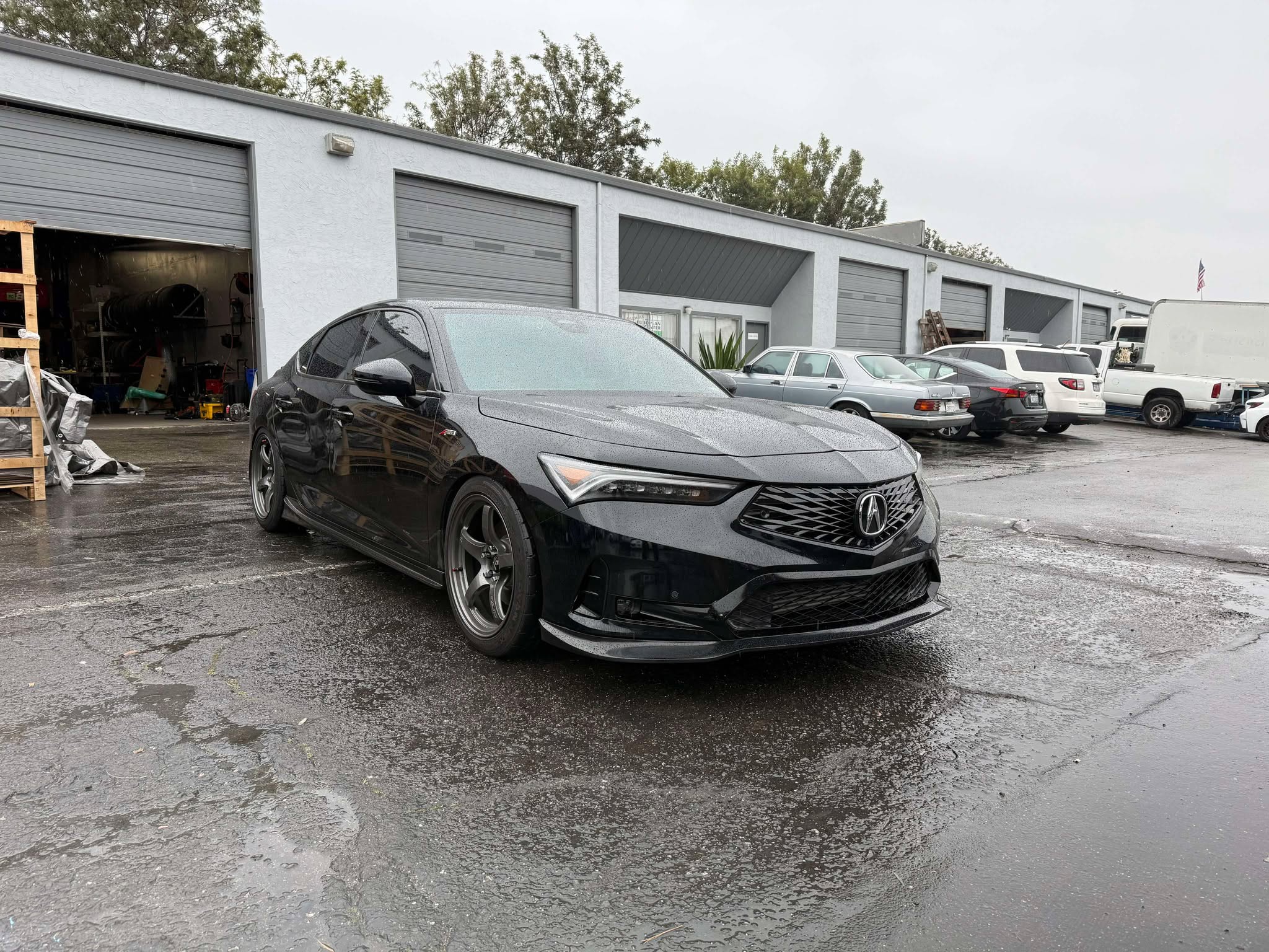 Black Acura Integra with front lip parked on a wet lot