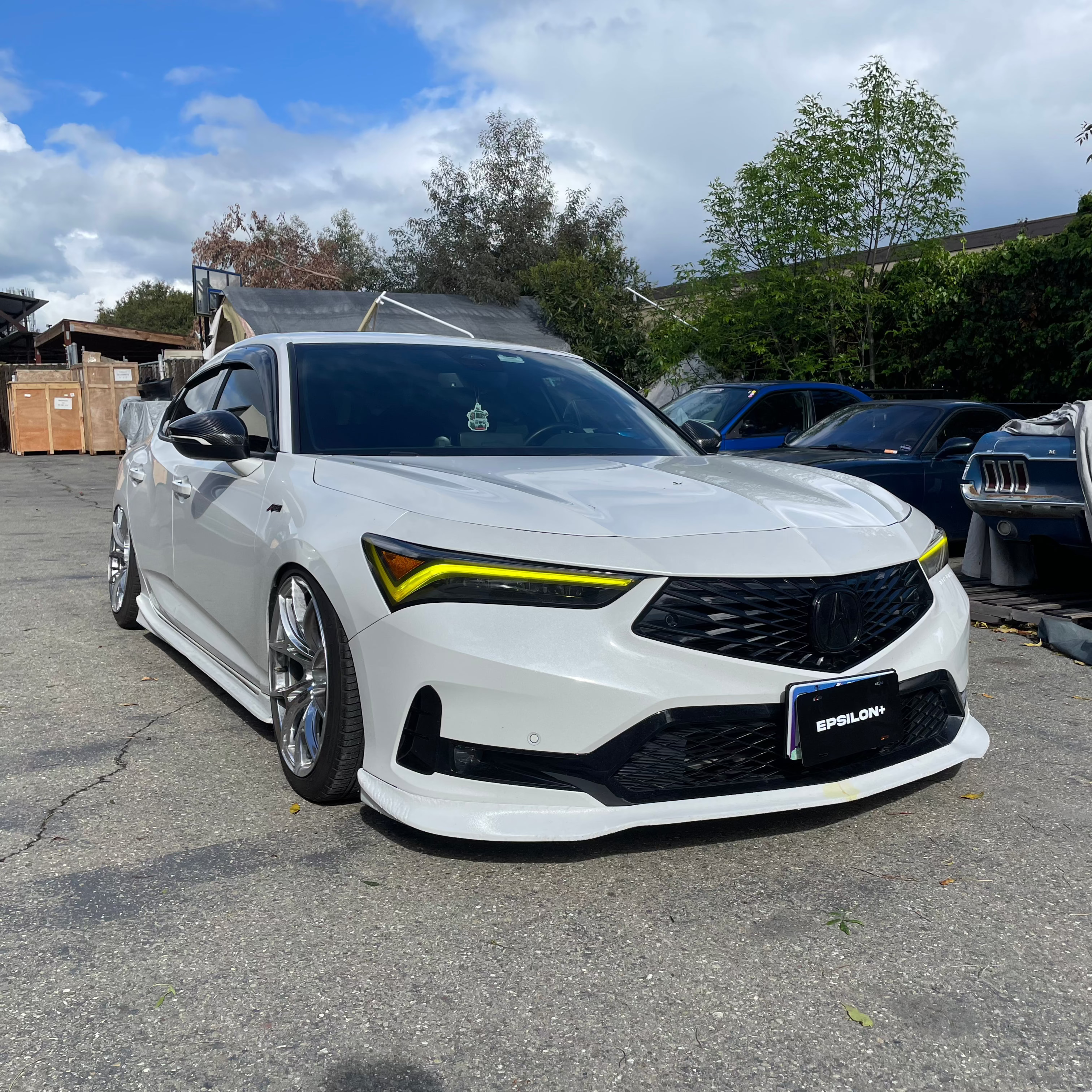 Front three-quarter view of a white Acura Integra with front lip and yellow accents