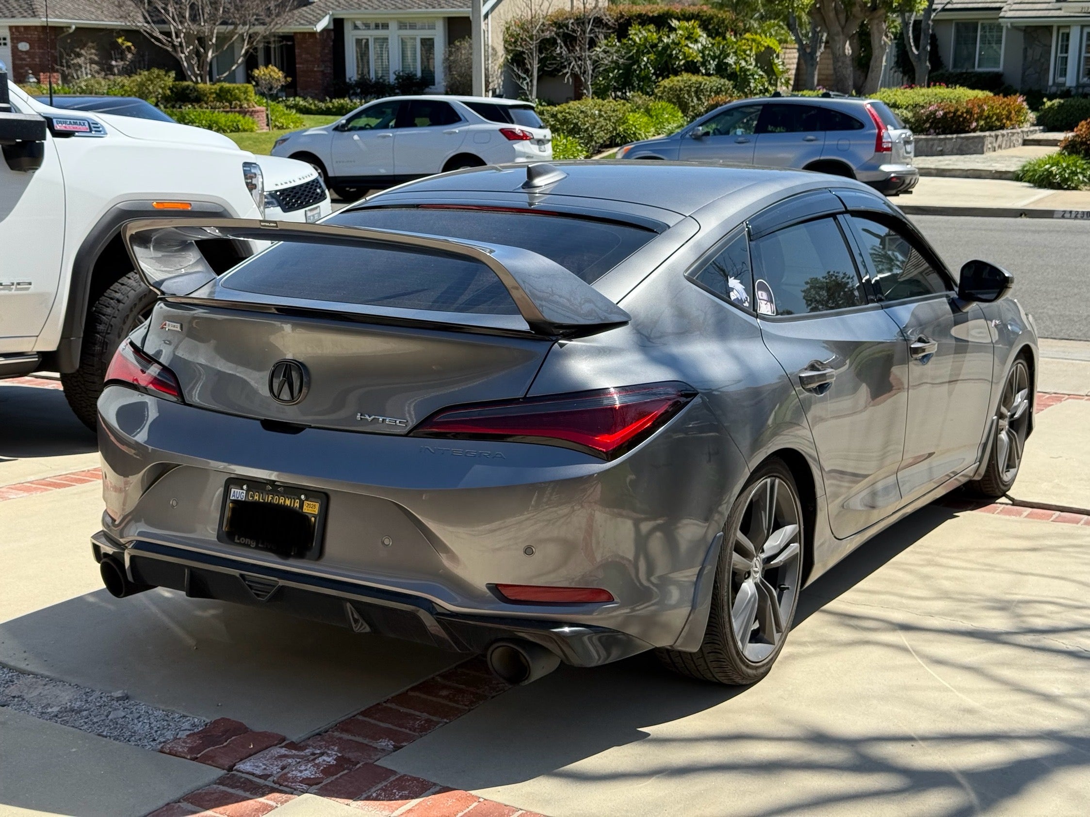 Rear three-quarter view of a champagne Acura Integra with the Sport Wing