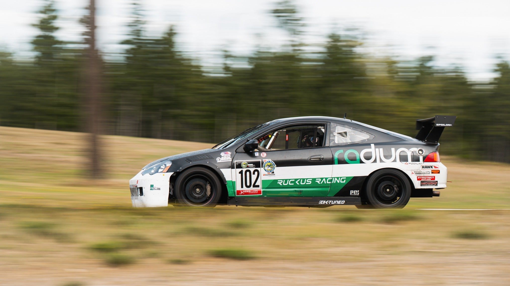 Gray Acura RSX motorsport car with GT wing panning shot on a road course