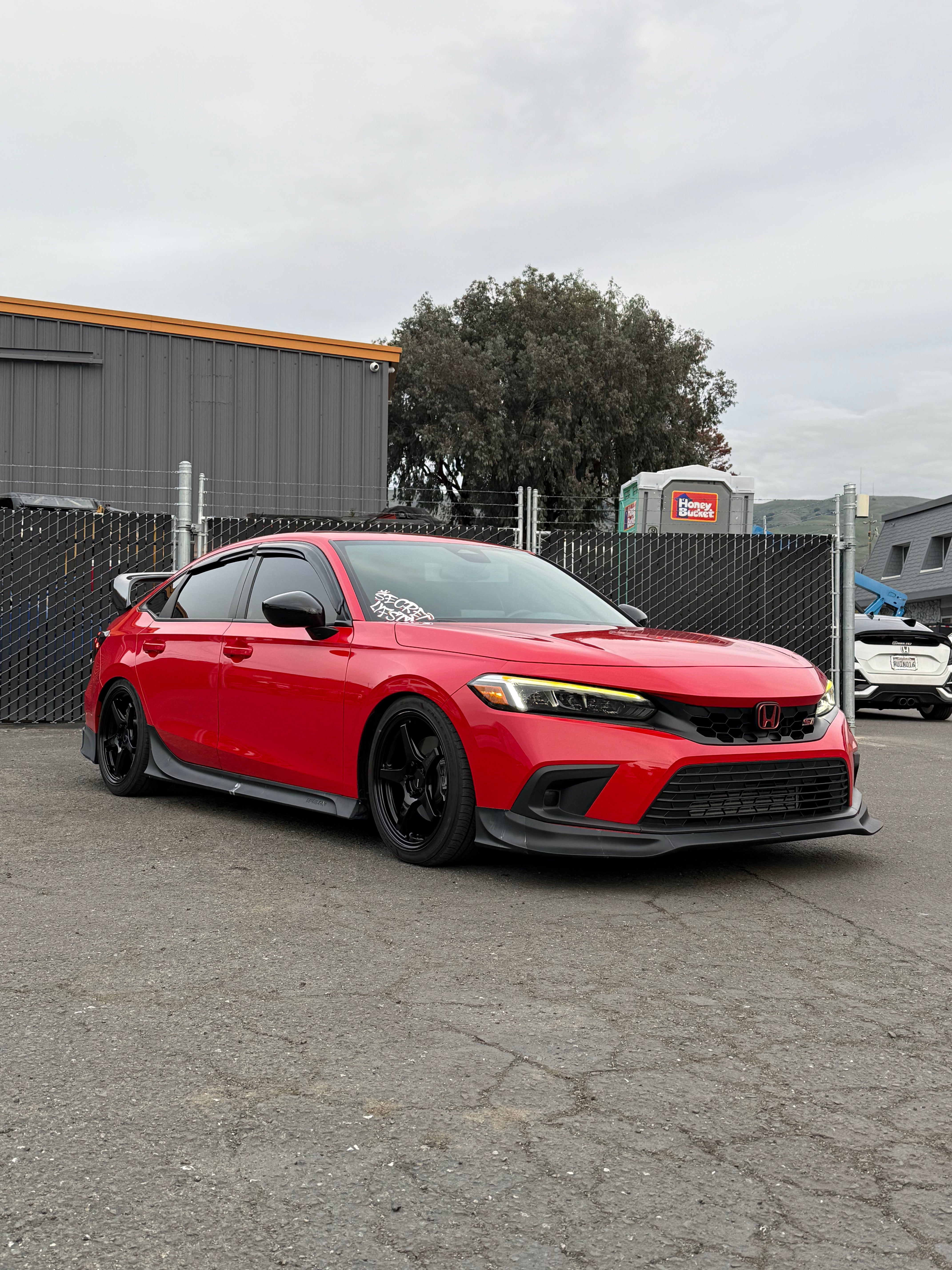 Red Honda Civic with the Epsilon+ side skirts and front lip in a lot