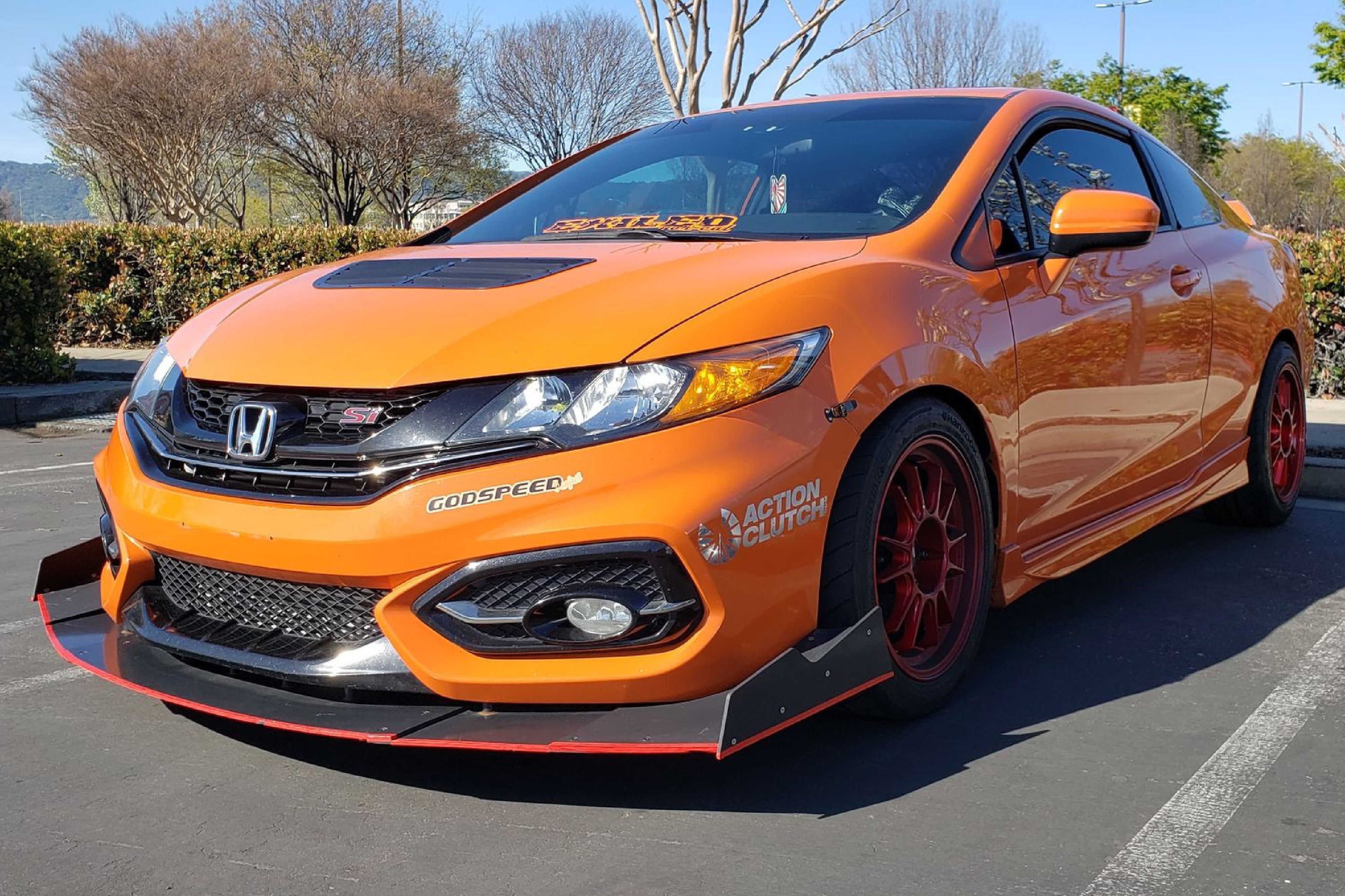 Front three-quarter view of an orange Civic Si Coupe FG4 with front splitter and red wheels