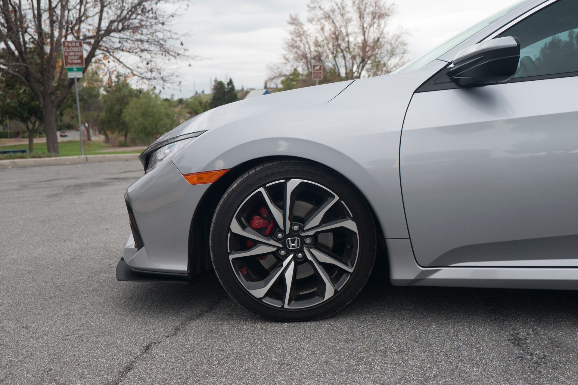 Close-up of the front lip's wheel-well fitment on a silver Civic Si