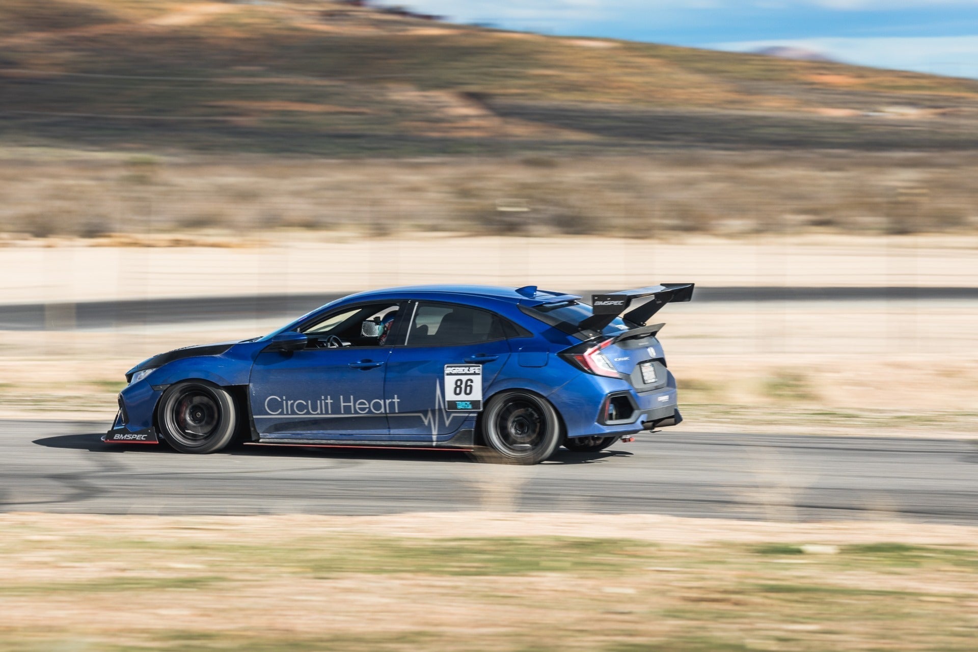 Civic Type R motorsport car with 'Circuit Heart' livery cornering hard, GT wing visible