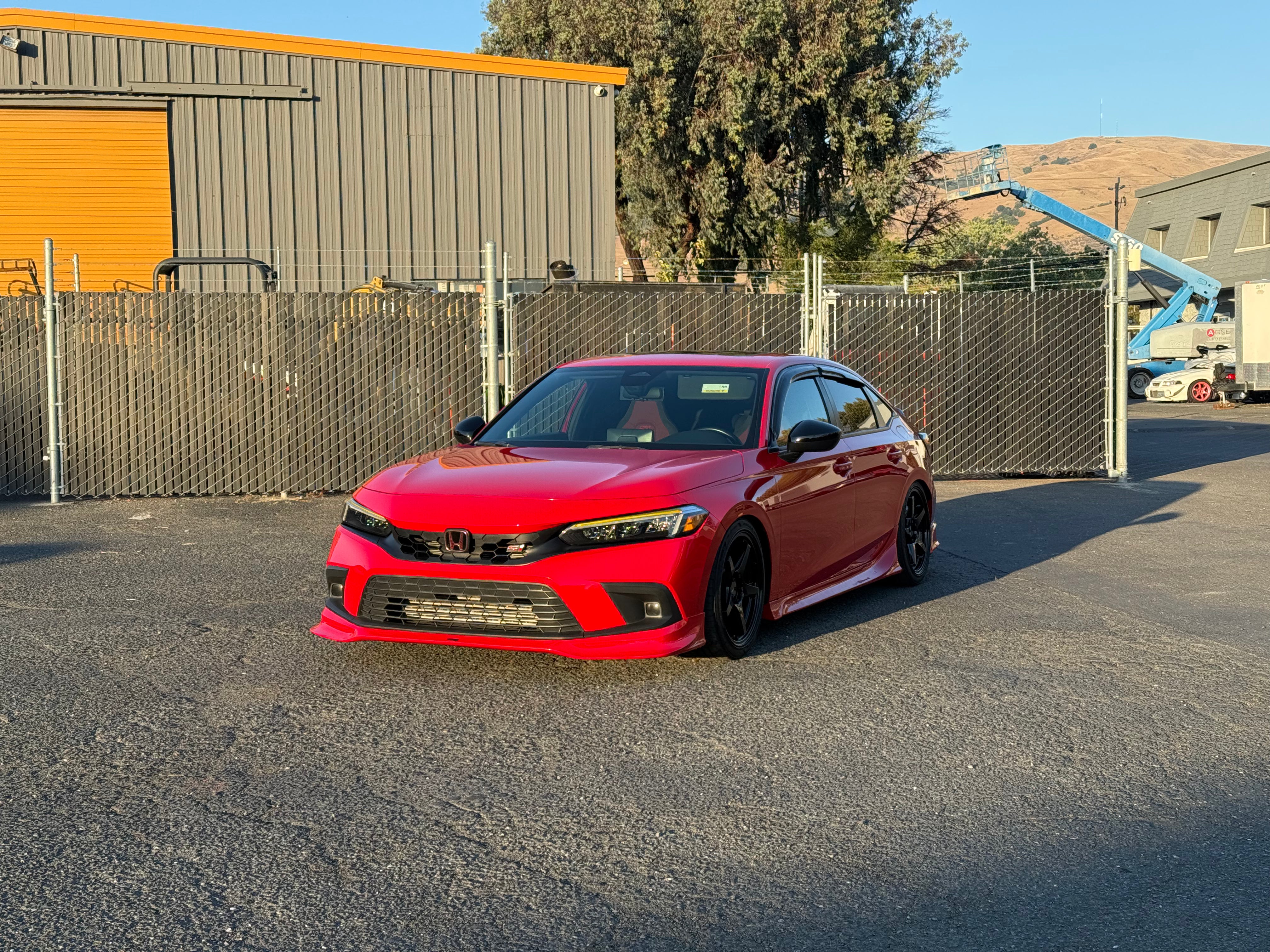 Red Honda Civic Zenki with front lip parked outside an industrial unit