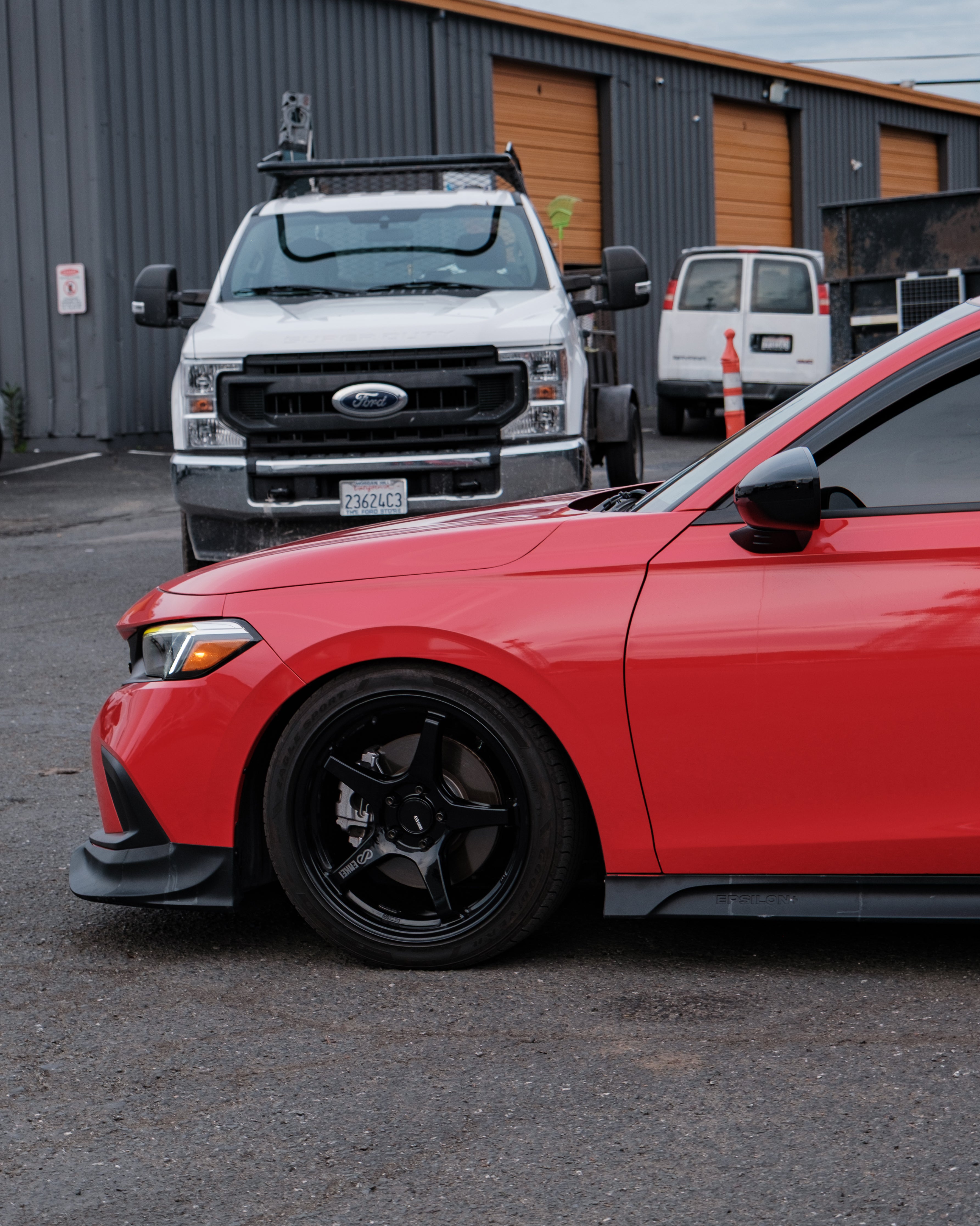 Red Honda Civic with the Epsilon+ front lip in an industrial parking lot