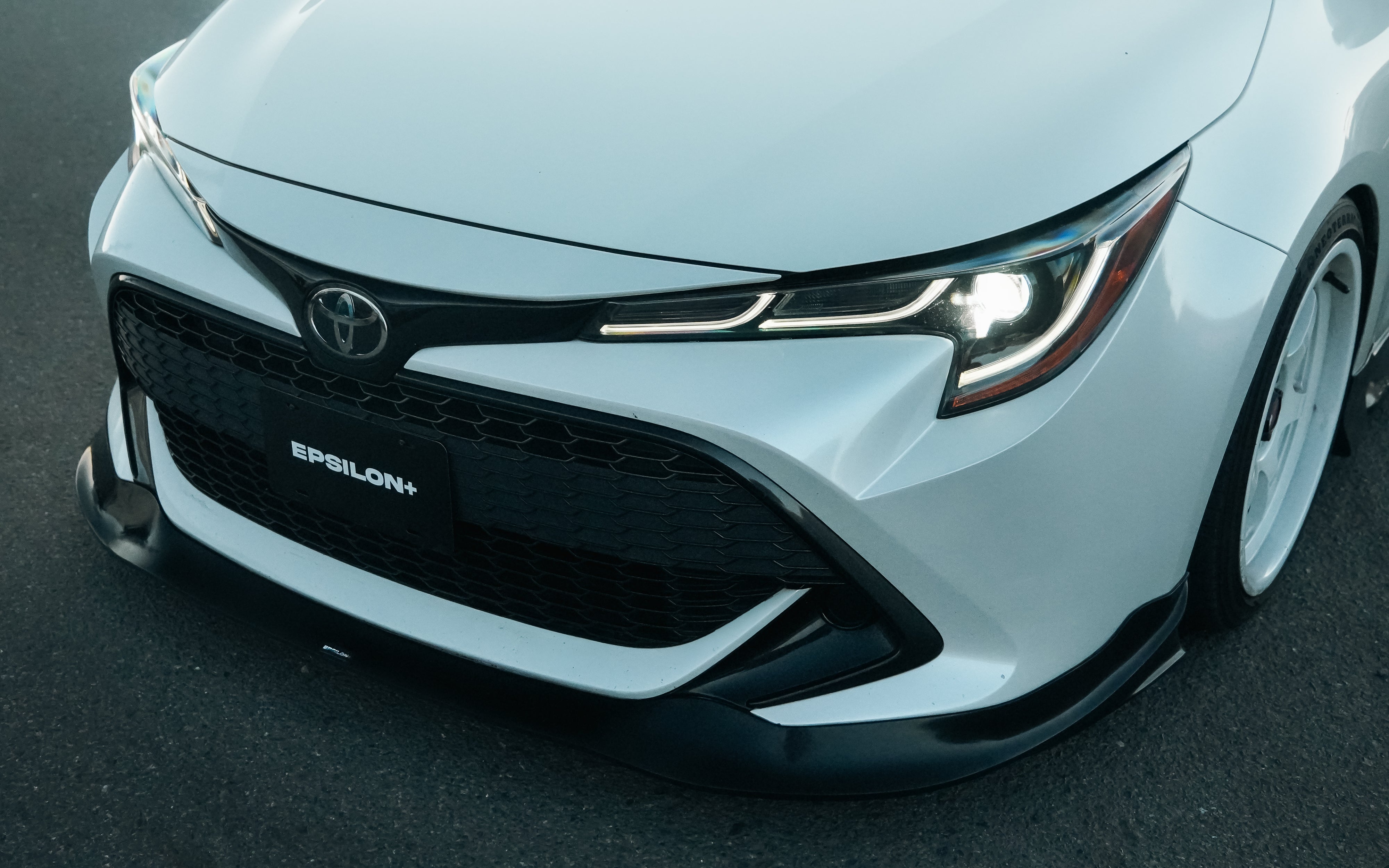 Close front view of the Epsilon+ front lip and branding on a white Corolla Hatchback