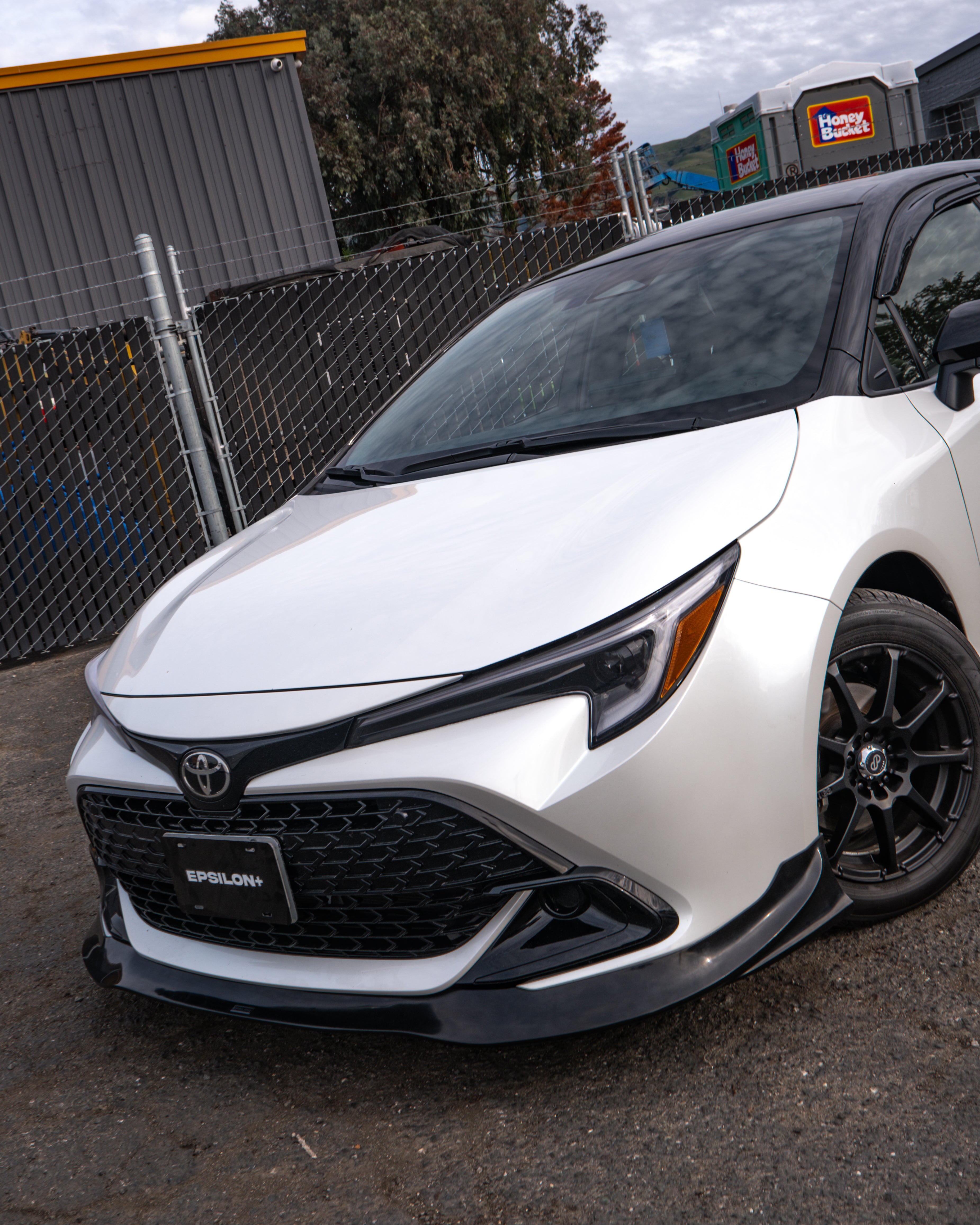 White Corolla Hatchback Kouki with front lip parked beside a warehouse