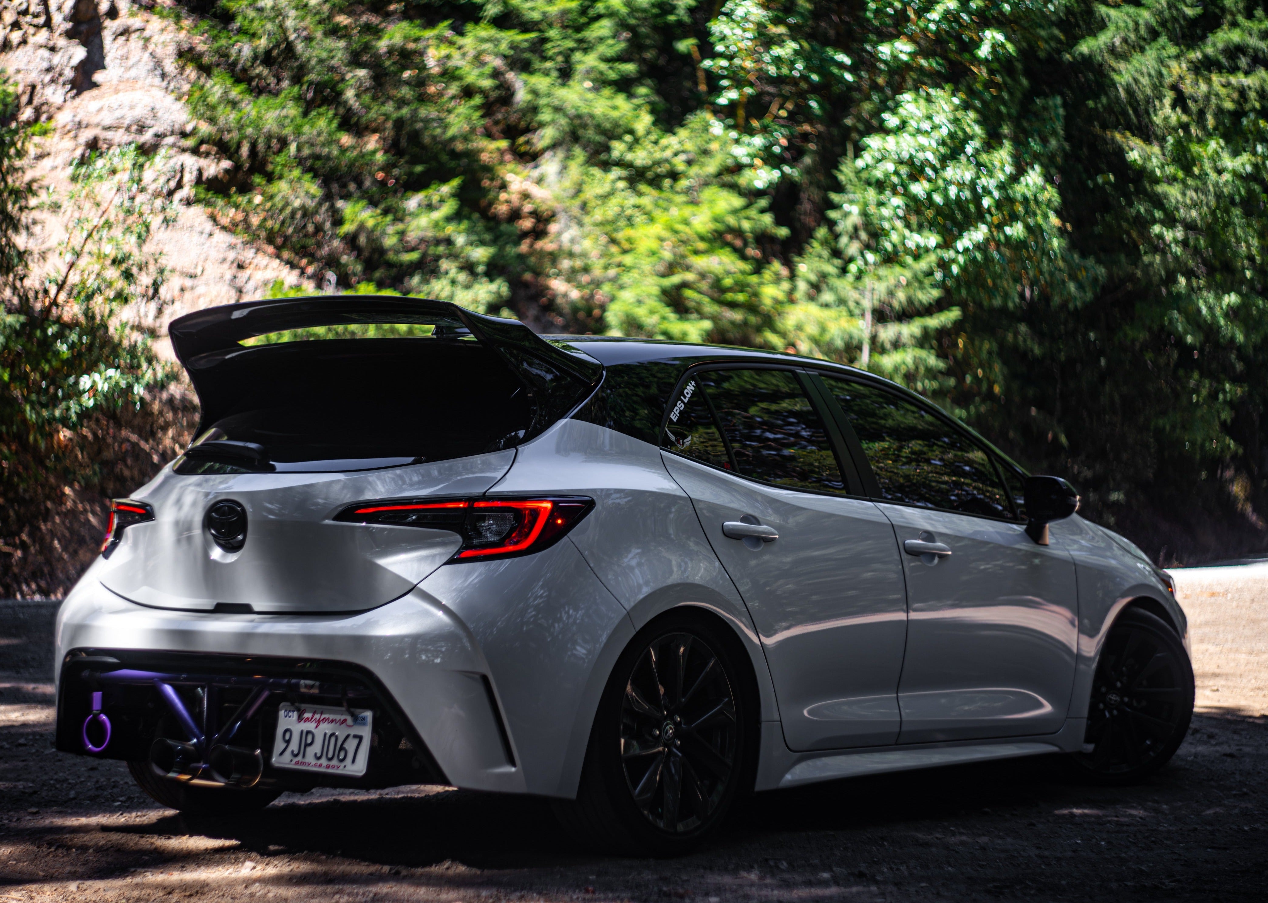 Rear three-quarter view of a silver Corolla Hatchback with WRC Wing V3 in a driveway