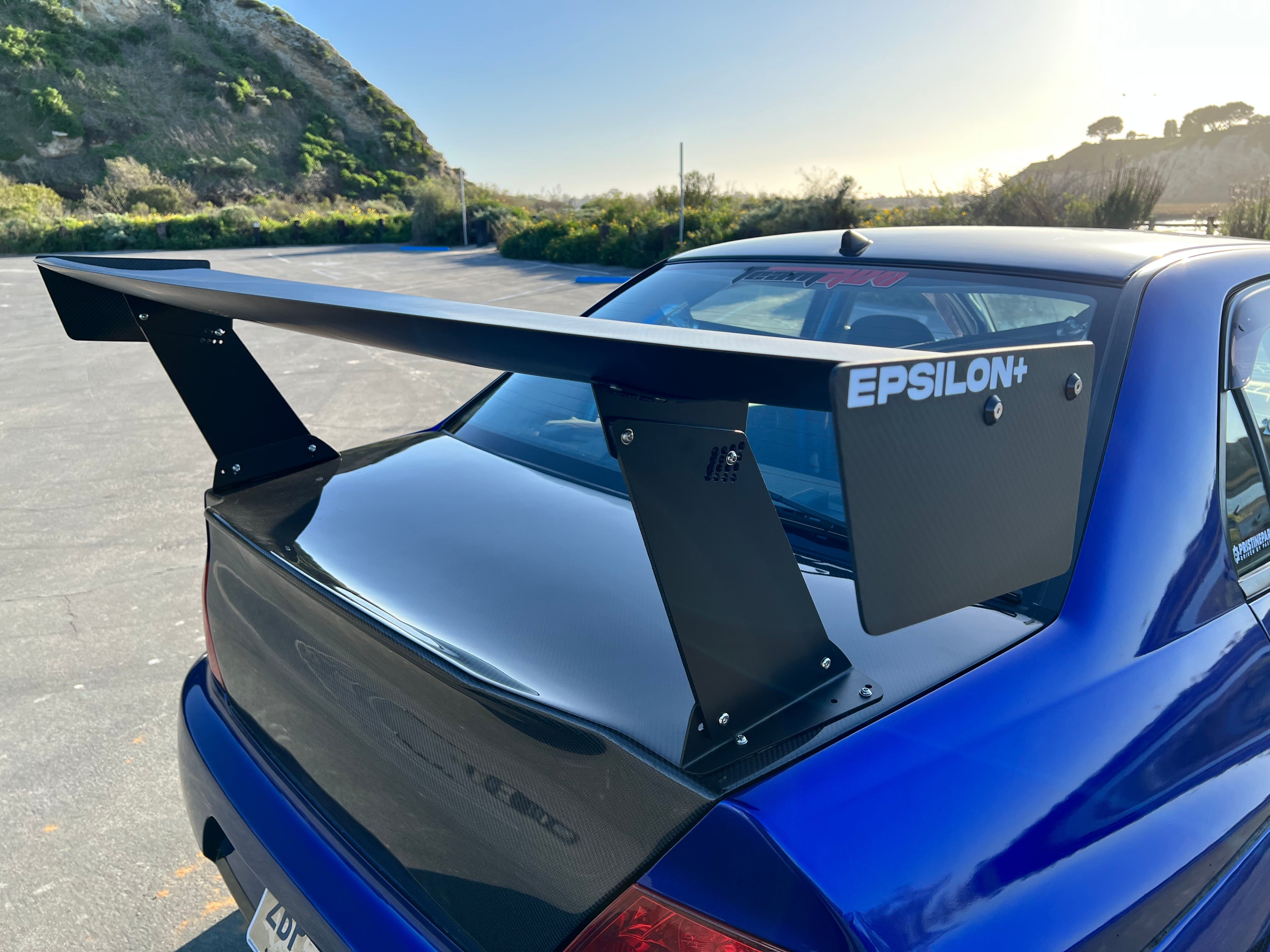 Close-up of the Epsilon+ GT wing mount on a blue Mitsubishi Evo trunk