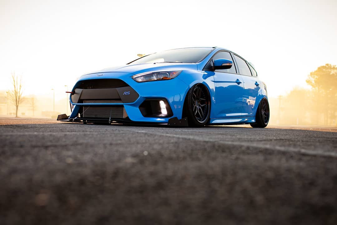 Front three-quarter view of a slammed blue Focus RS with front splitter at sunset