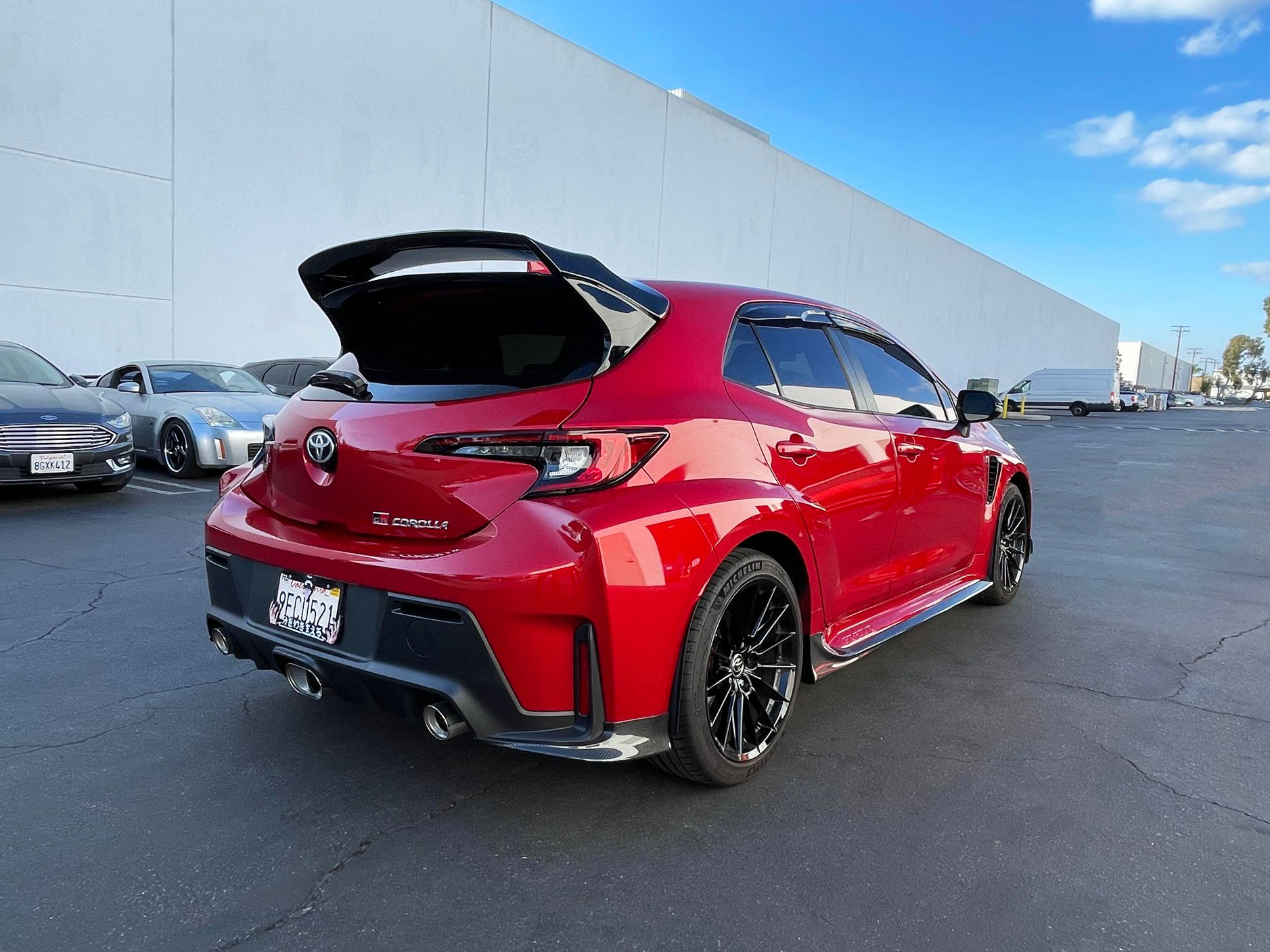 Rear three-quarter view of a red GR Corolla with side skirts and rear spats
