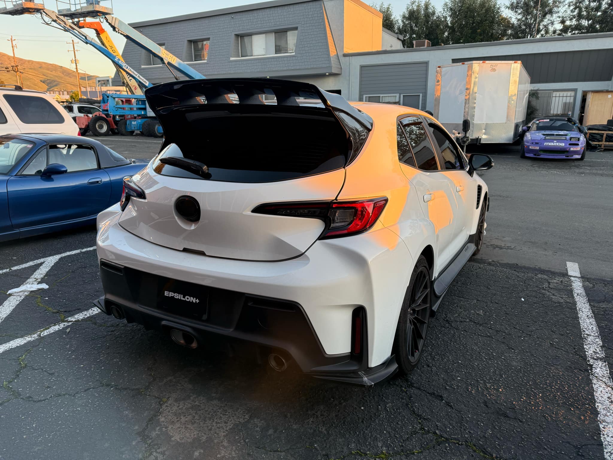 Rear view of a white GR Corolla with WRC Wing Strakes V2 in a parking lot
