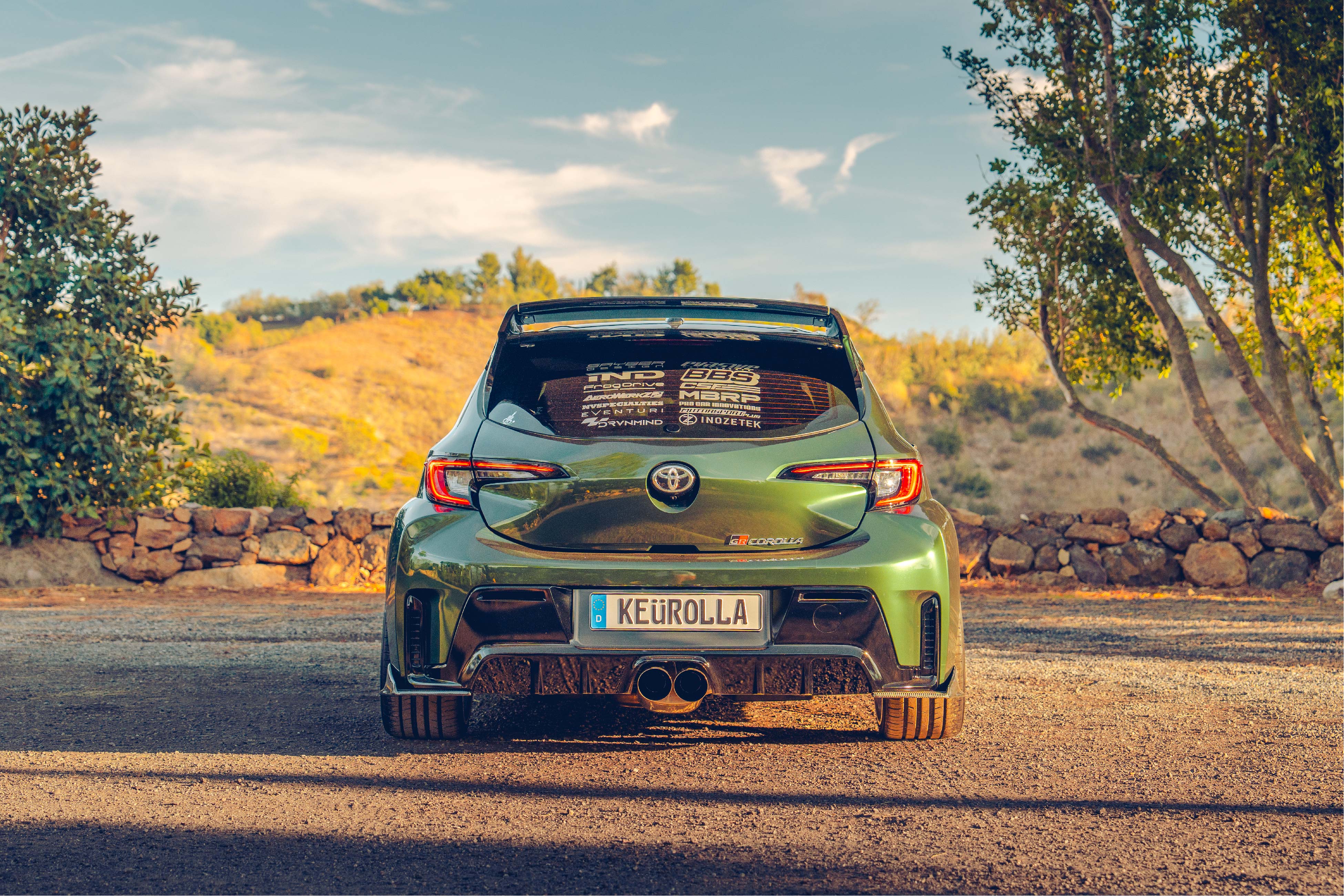 Rear view of a green GR Corolla with WRC Wing V3 on a rural road
