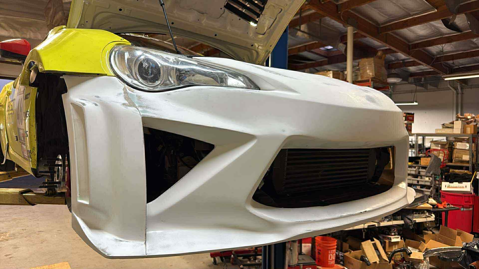White Epsilon+ front bumper fitted during bodywork in the shop