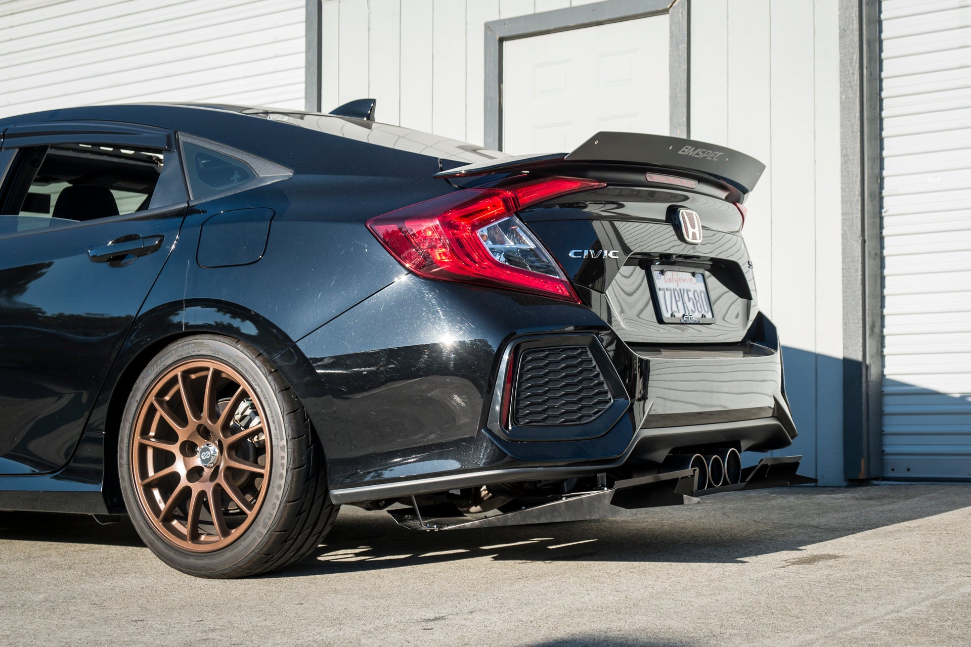 Rear three-quarter view of a black Civic Si Sedan with diffuser and quad exhaust tips