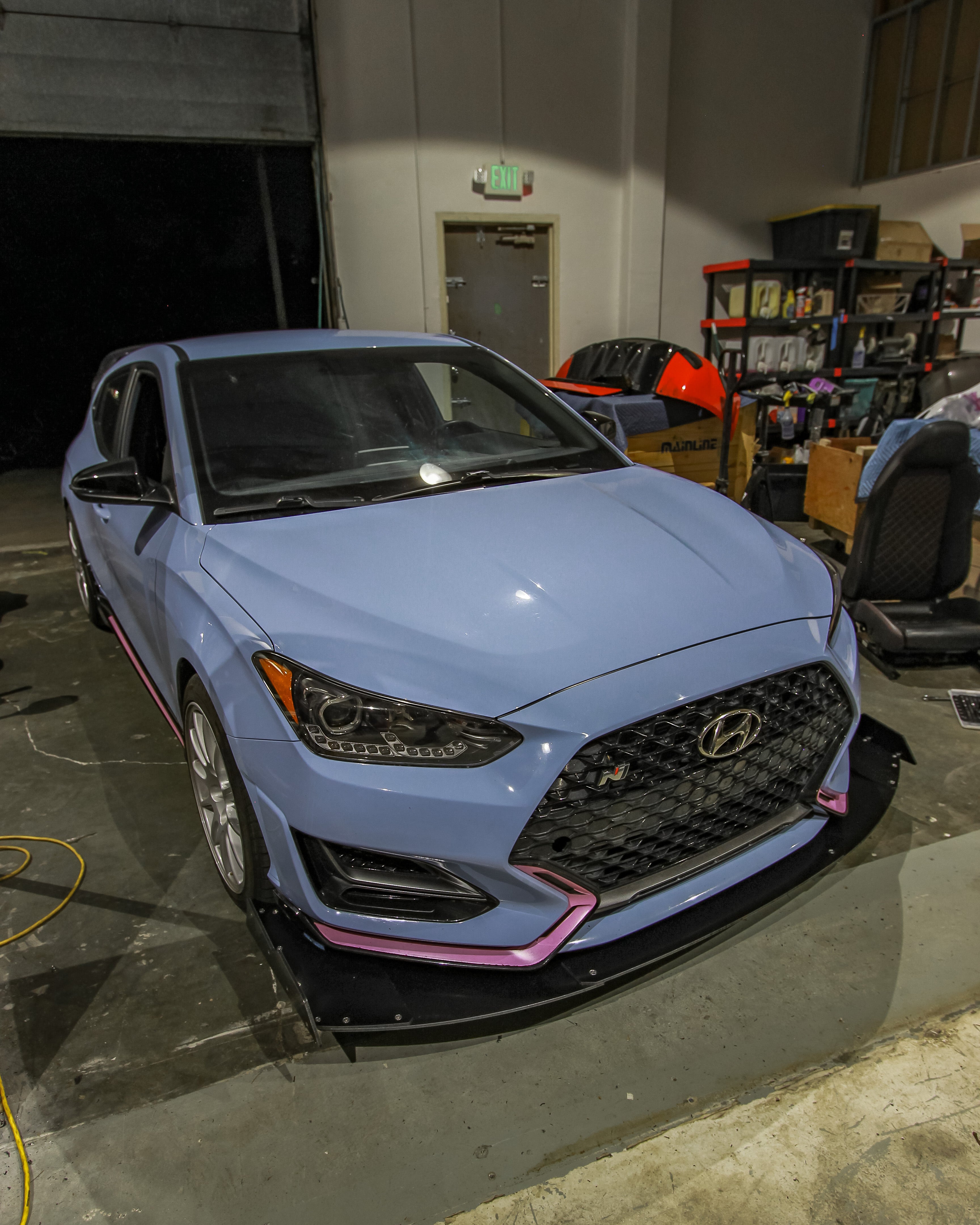 Light blue Hyundai Veloster N with V2 front splitter fitted in the workshop