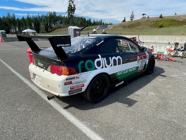 Rear three-quarter view of a black RSX race car with Epsilon+ GT wing in the paddock