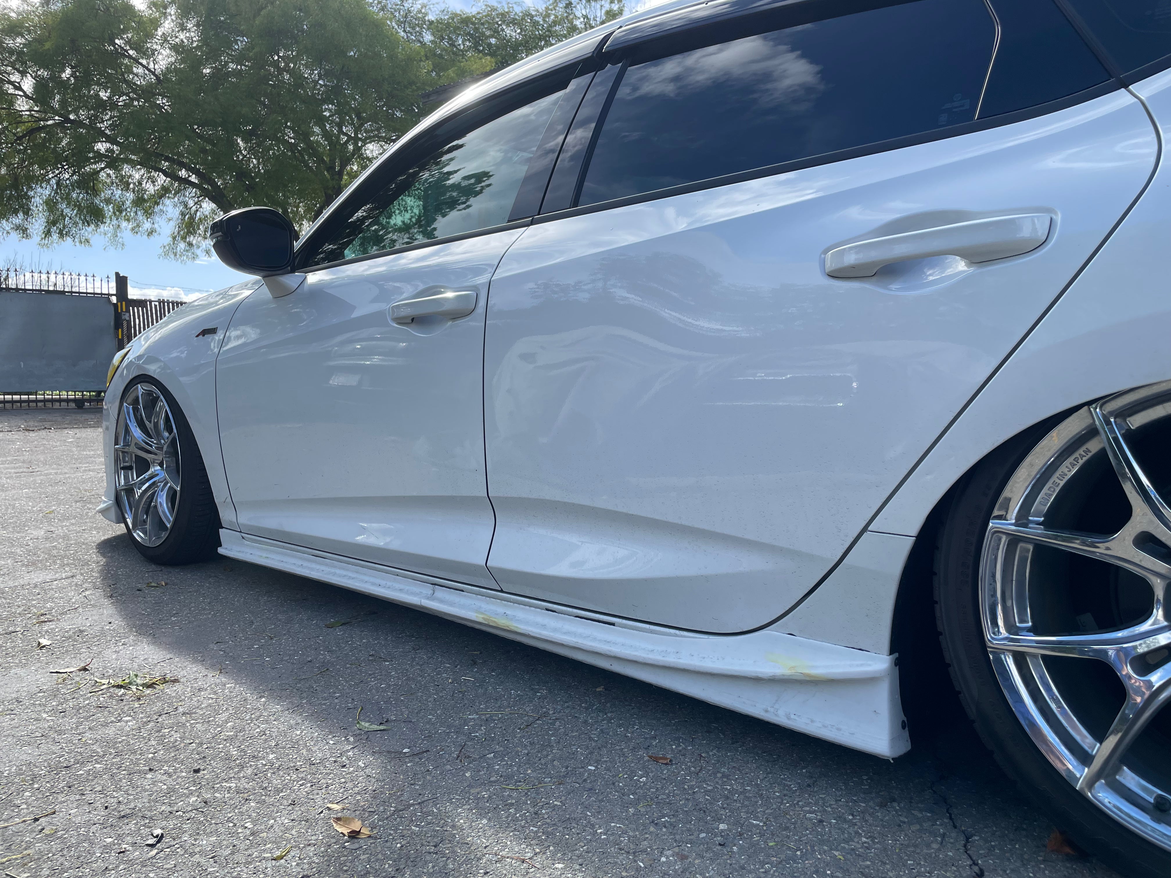 Low side view of a white Acura Integra showing the side skirt profile