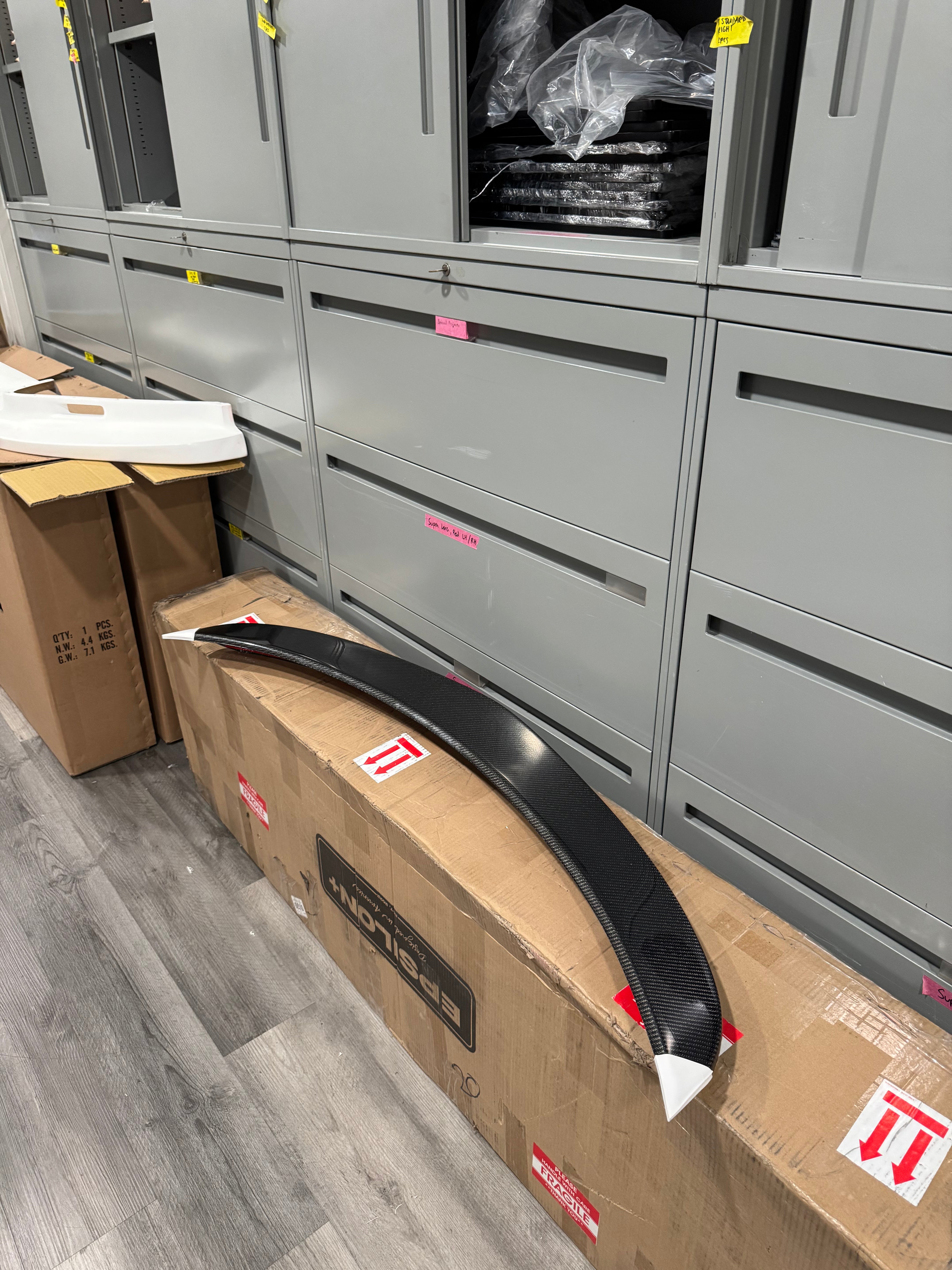 Carbon fiber Epsilon+ rear trunk lip packaged in its shipping box